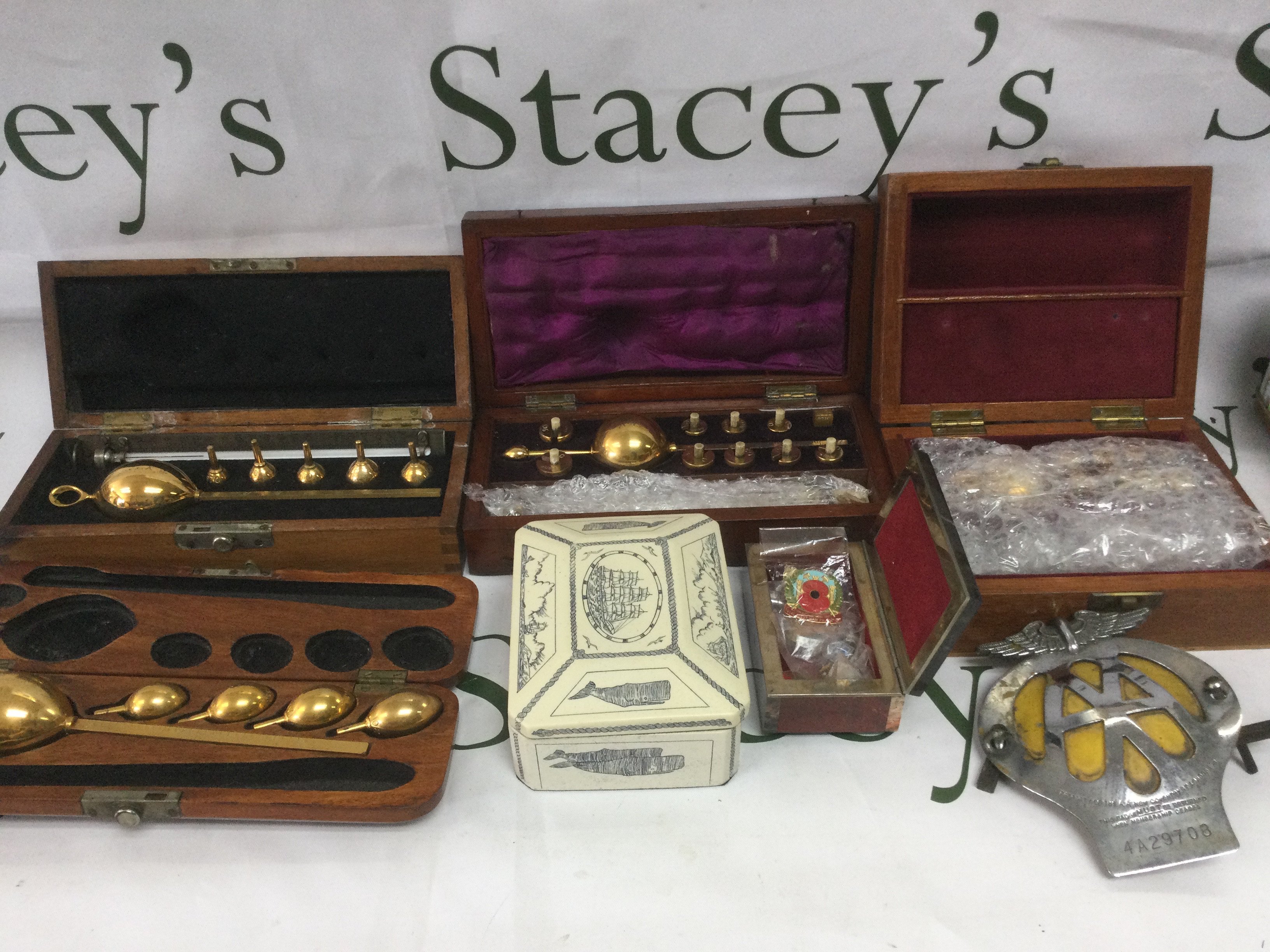 A box of oddments including brass weights, AA car badge, lava lamp etc. Shipping category D.