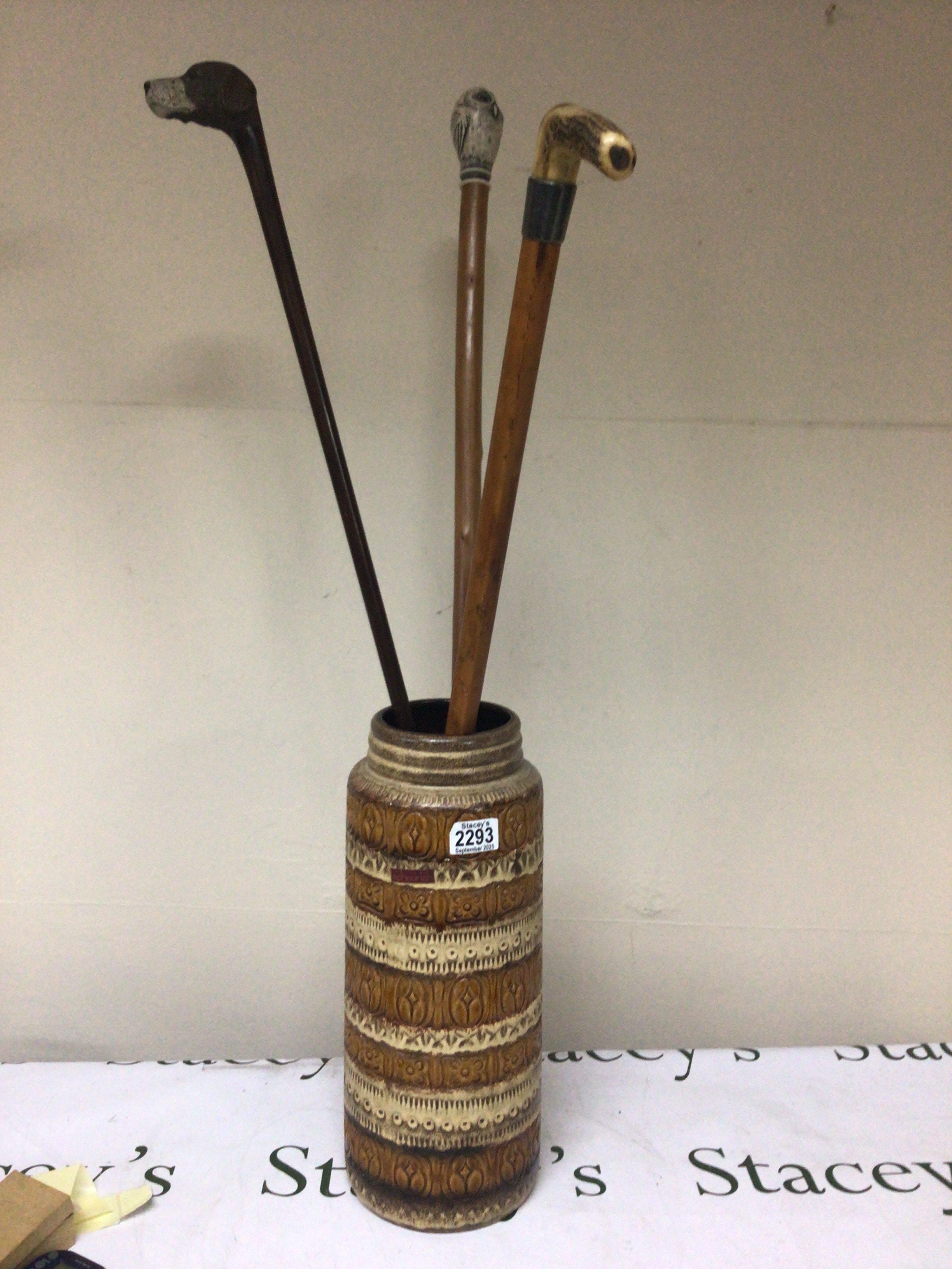 A German Mid 20th century floor vase with three walking sticks one with a silver collar one carved and painted dogs head and an owl (3)