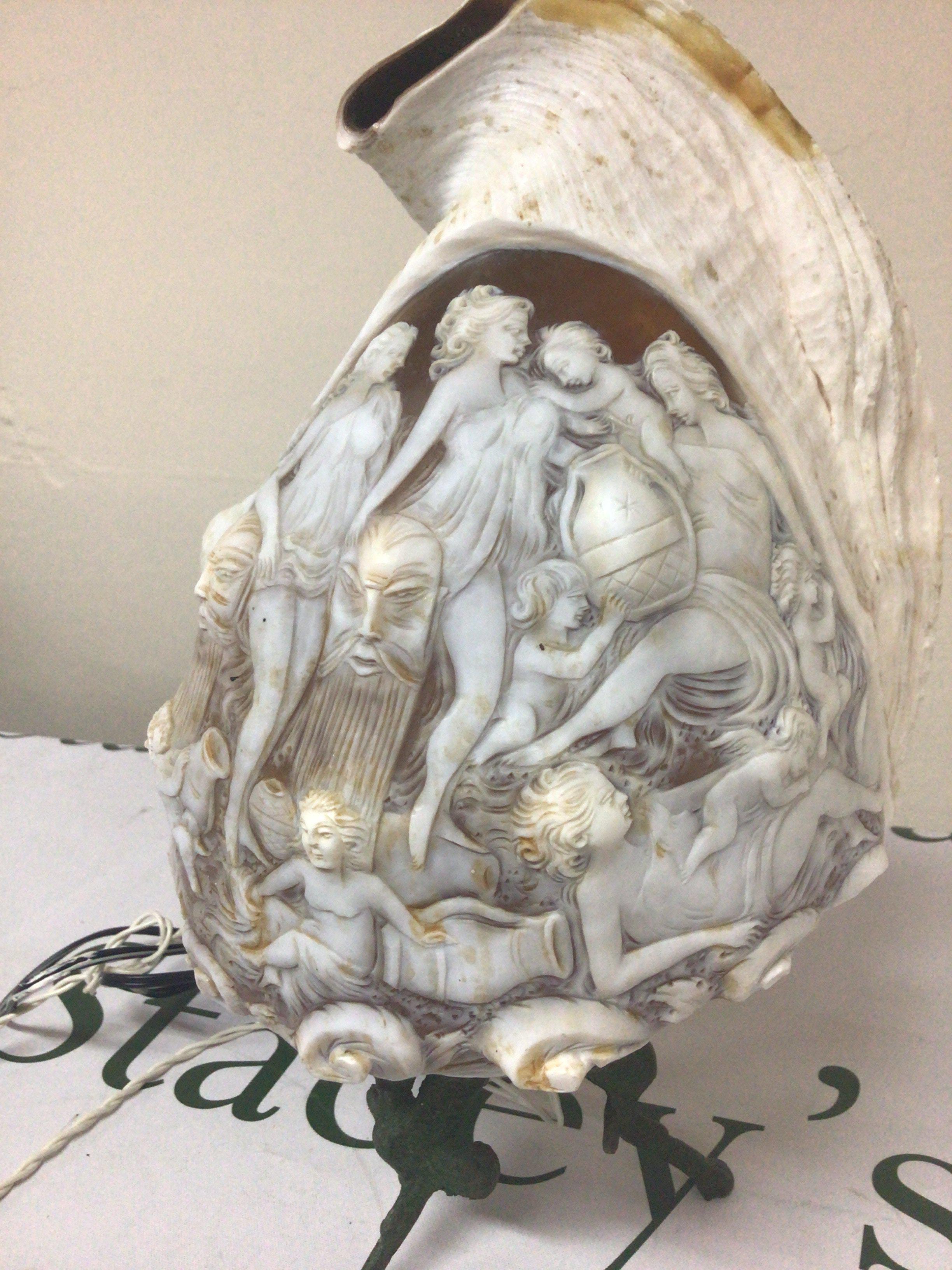 A quality Carved Cameo Conch shells on a metal stand. The shell carved with neo-classical female figure with raised masks. Total hight including stand 28cm. later fitted for electric.