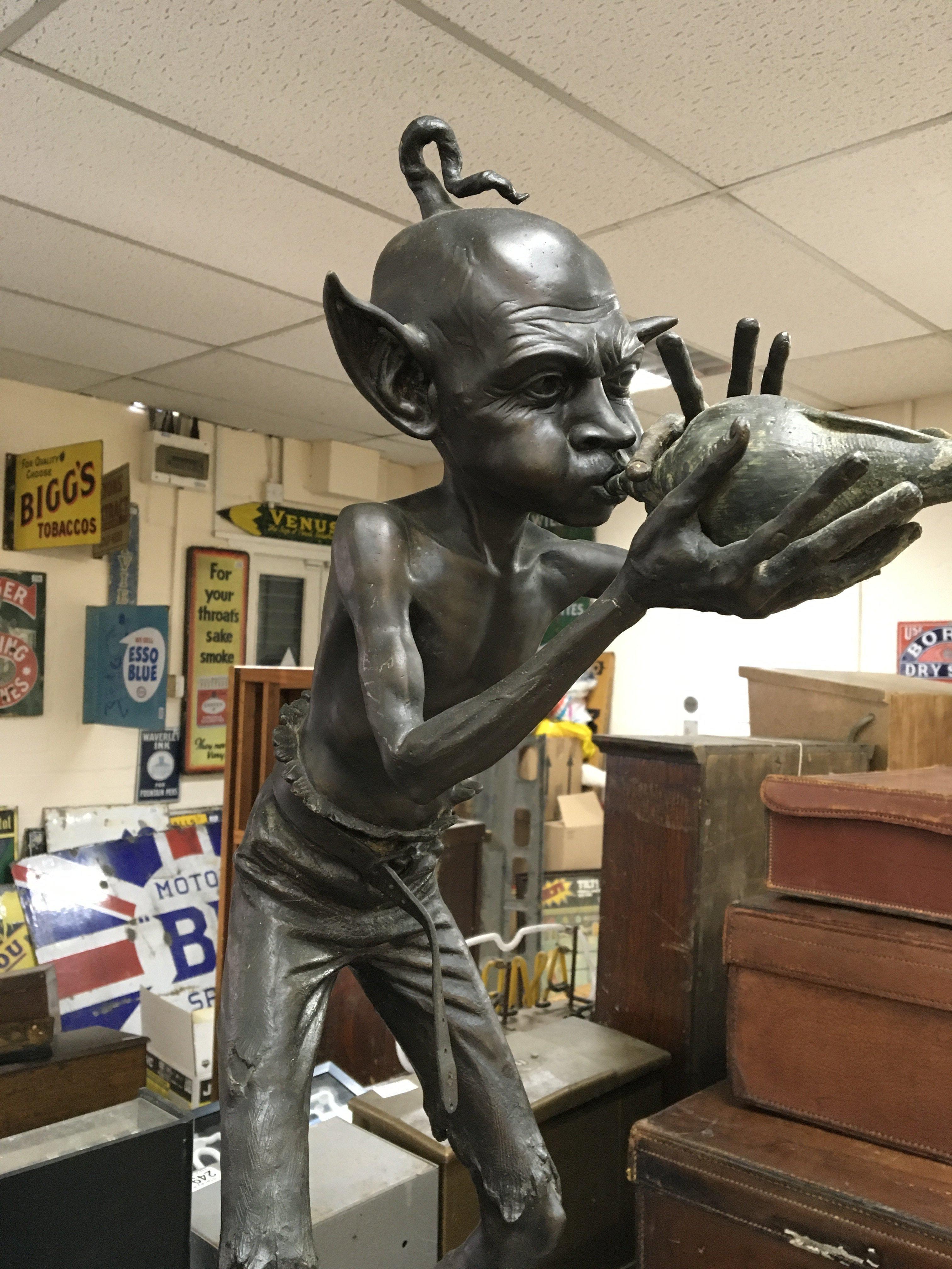 In the style of David Goode, a bronze figure in the form of a goblin playing a conch shell 84 cm