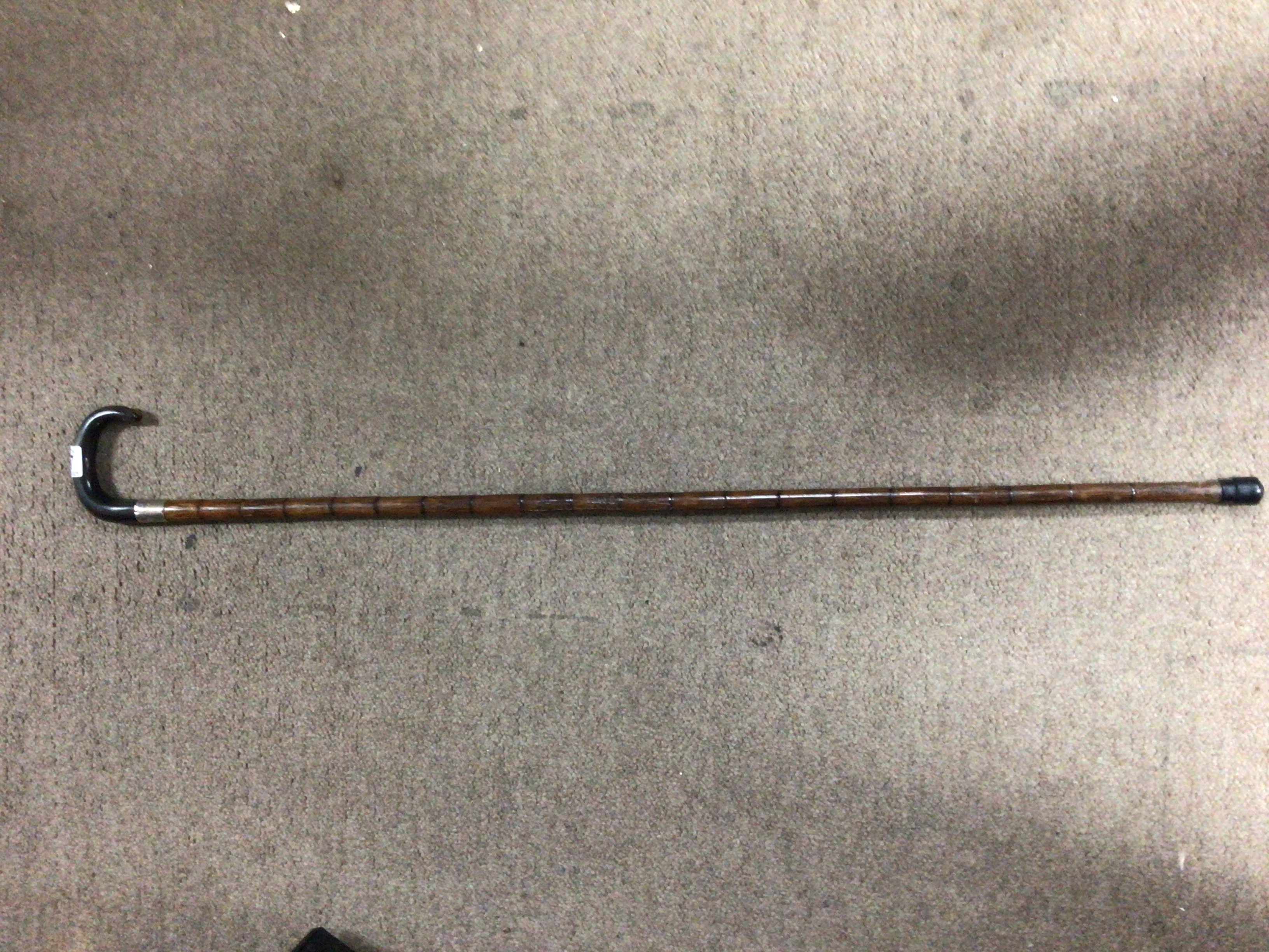 An antique walking stick with a metal cuff round the handle and stick.