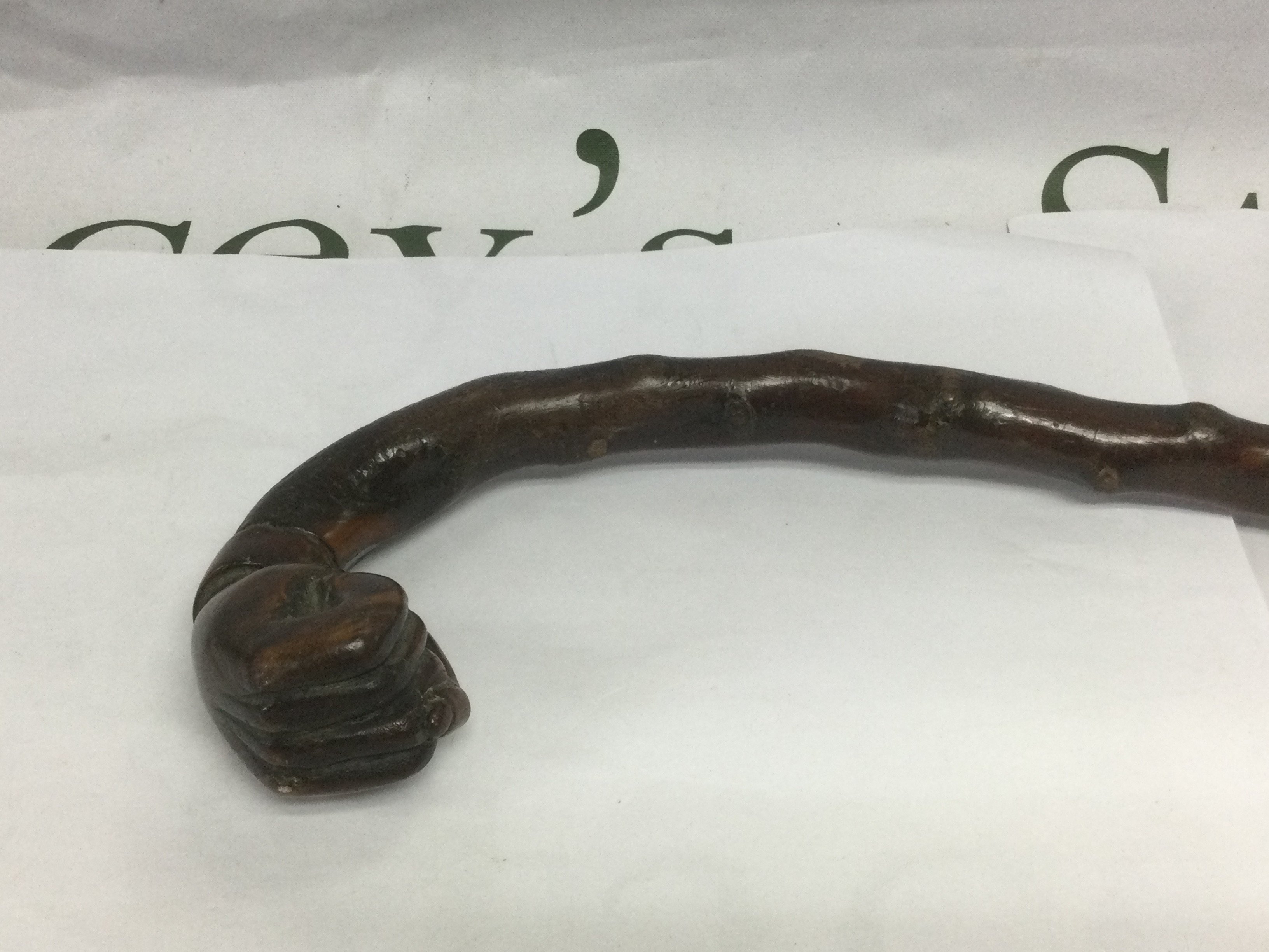 A walking cane, the handle in the form of a clenched fist, approx total length 80cm. Shipping category D.