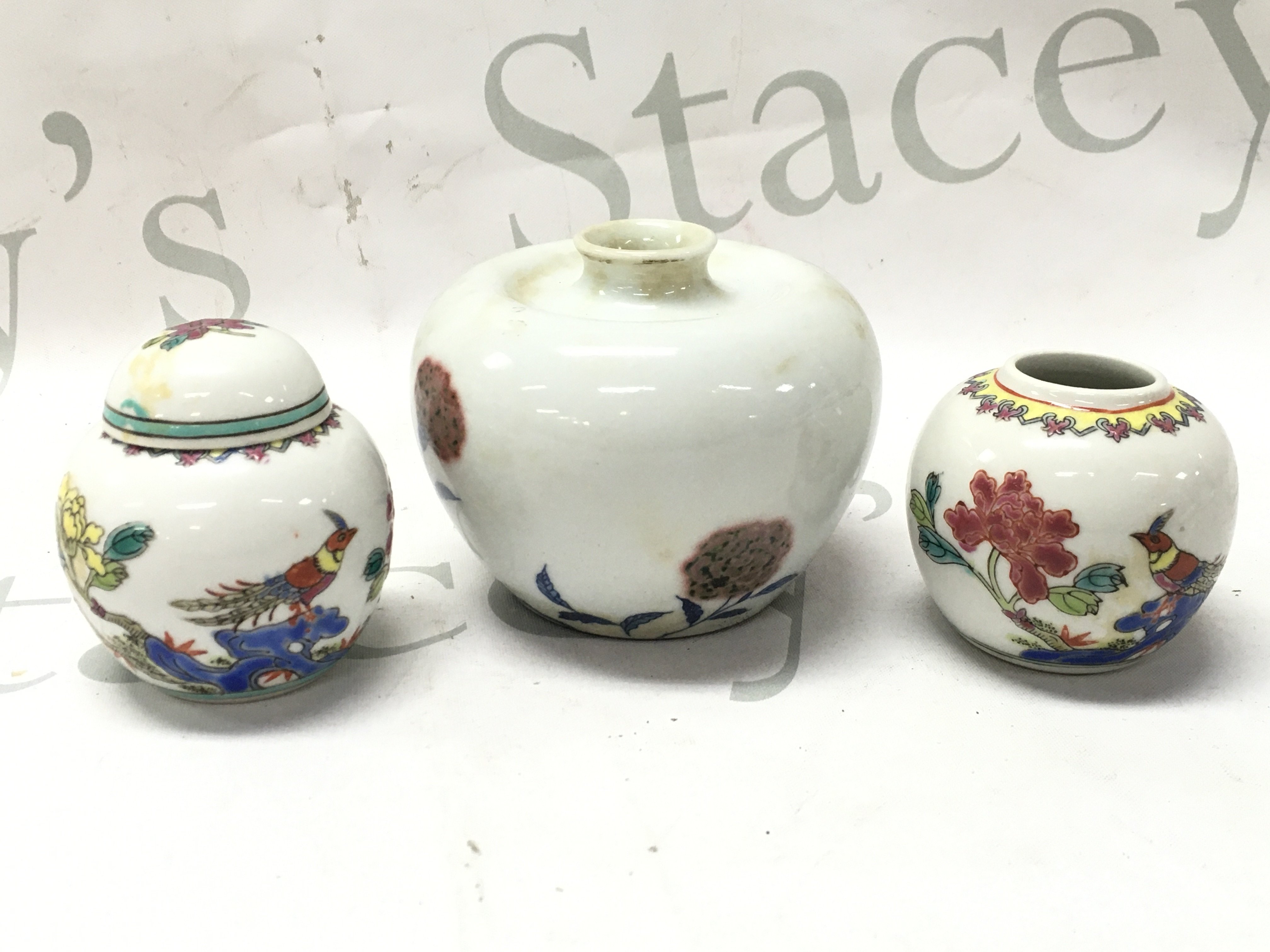 Three small Chinese jars including a pair of Famille rose jars (6cm tall 6cm wide), largest vase with a six character mark at base (8cm tall 9cm wide). This lot cannot be posted