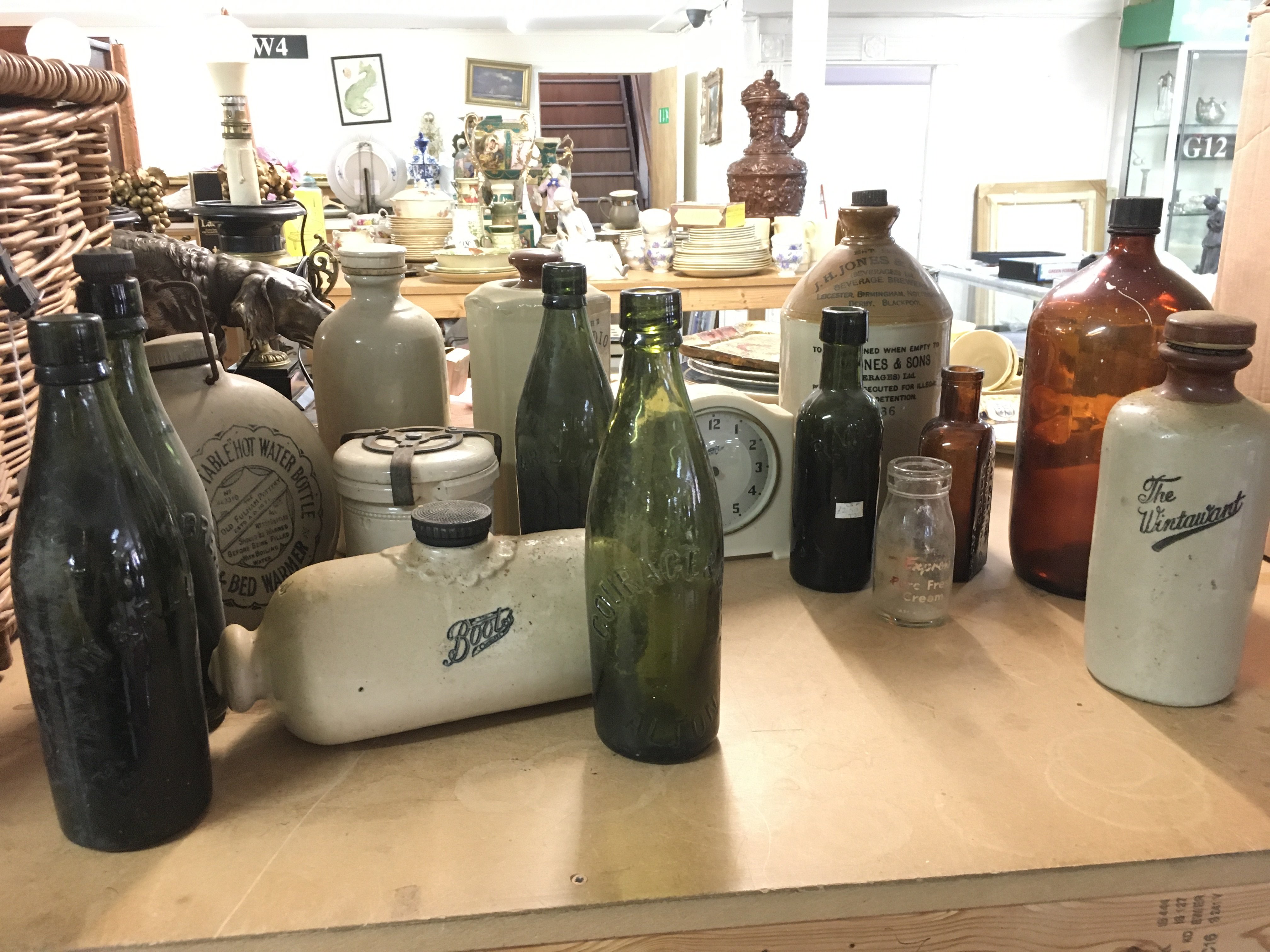 A collection of vintage glass green Bottles , J.H JONES & Sons beverage bottle, The Radio hot water bottle Etc