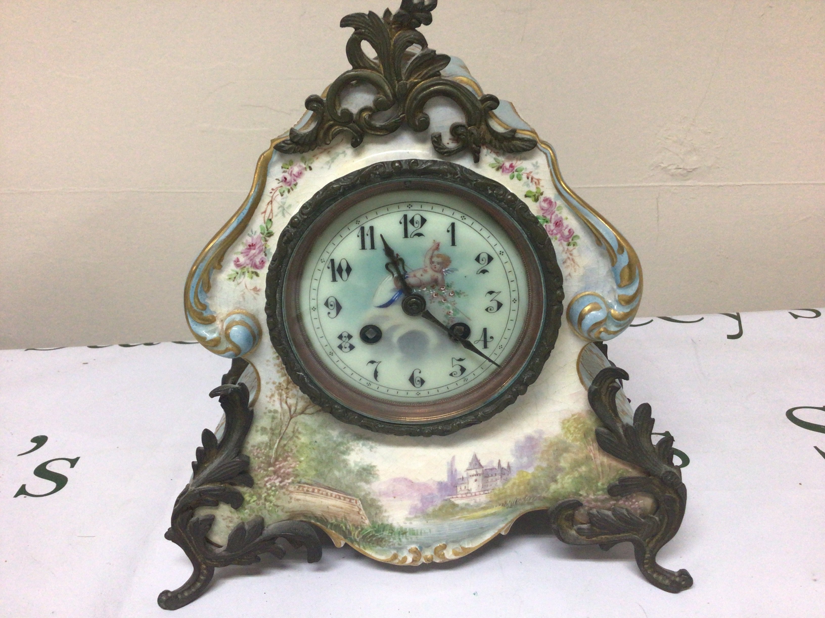 A French Early 20th Century porcelain clock painting with a view of a chateau with metal mounts. With one side ornament. Height