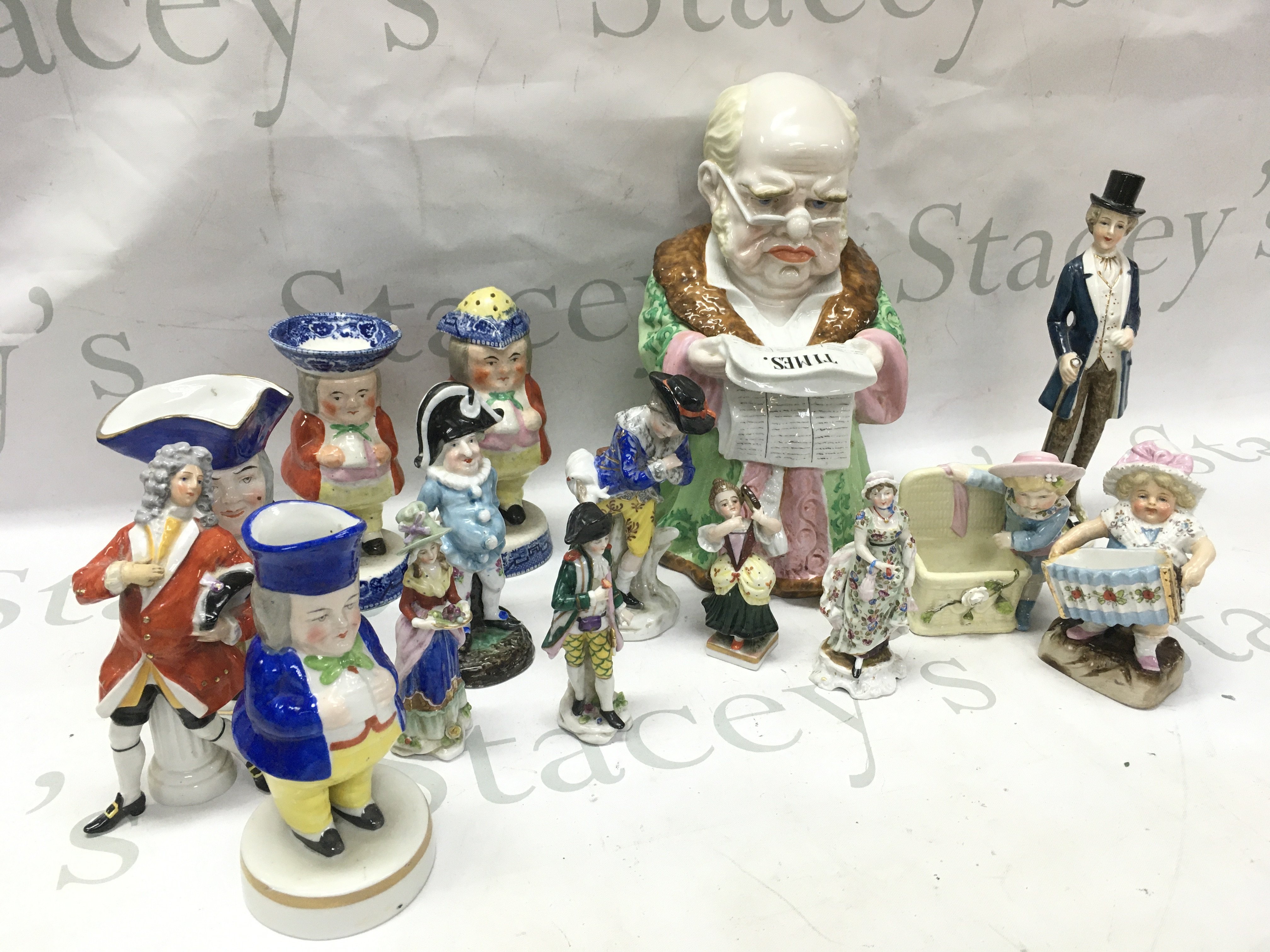 A collection of porcelain classical figures including a tobacco jar of a man reading The Times , miniature figures. This lot cannot be posted