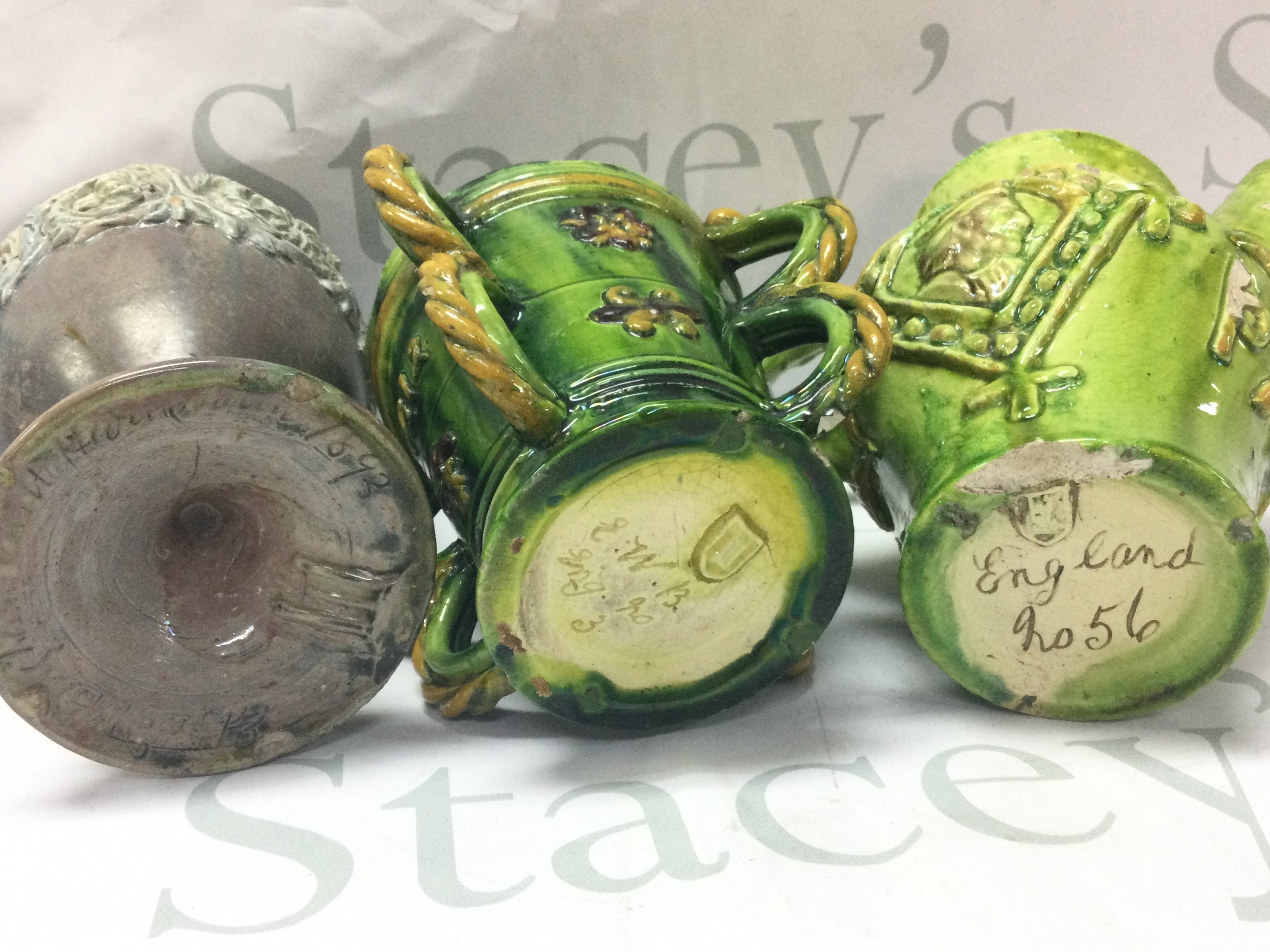 Three Castle Headingham pottery items including green and yellow glazed four handled jug and other jug and a goblet shaped vase . Tallest 18cm. This lot cannot be posted