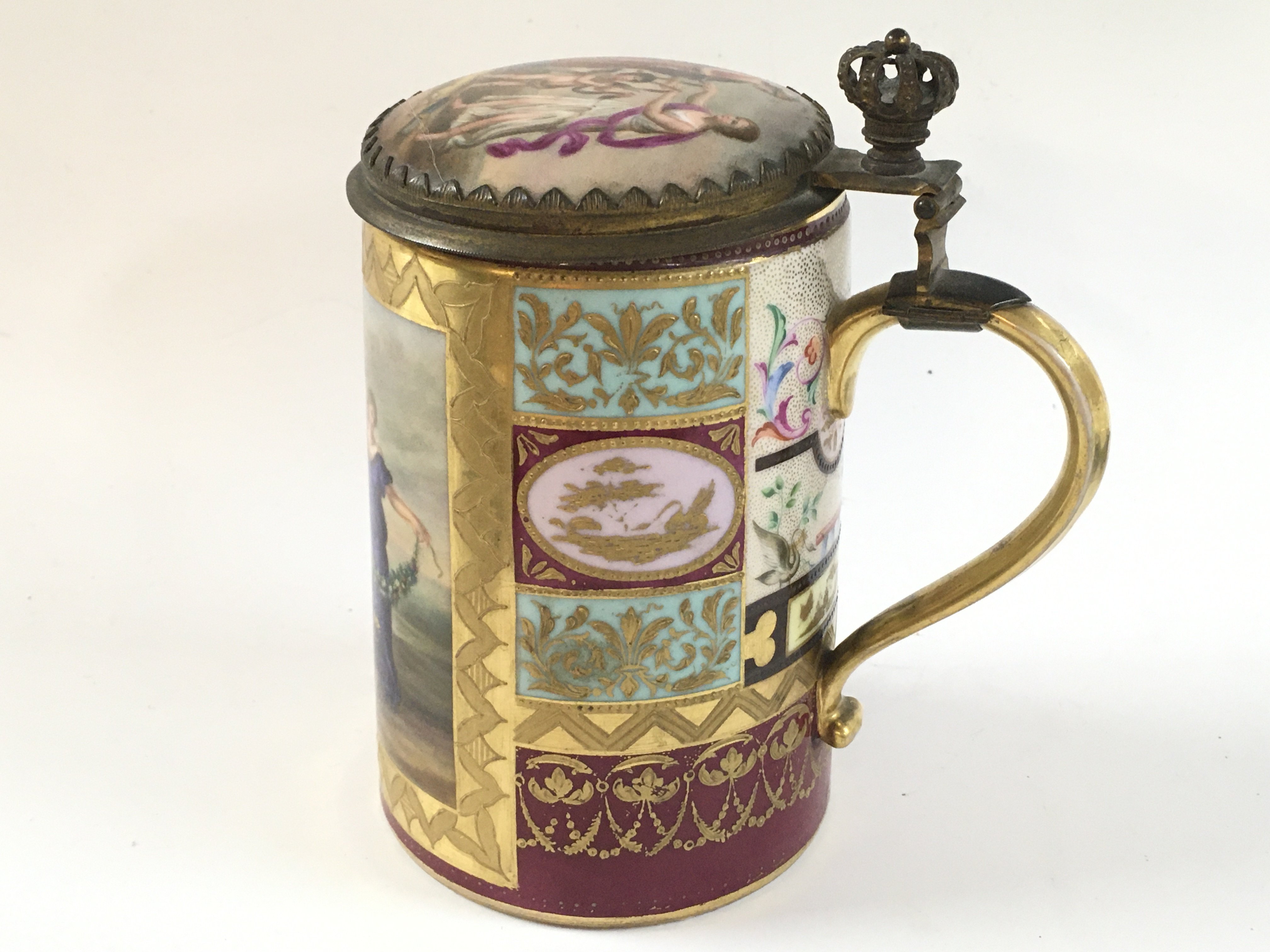 An early 20th century Vienna porcelain tankard with fine guilted detail and classical scene around the tankard, as well as interior designs on the inside of the lid.