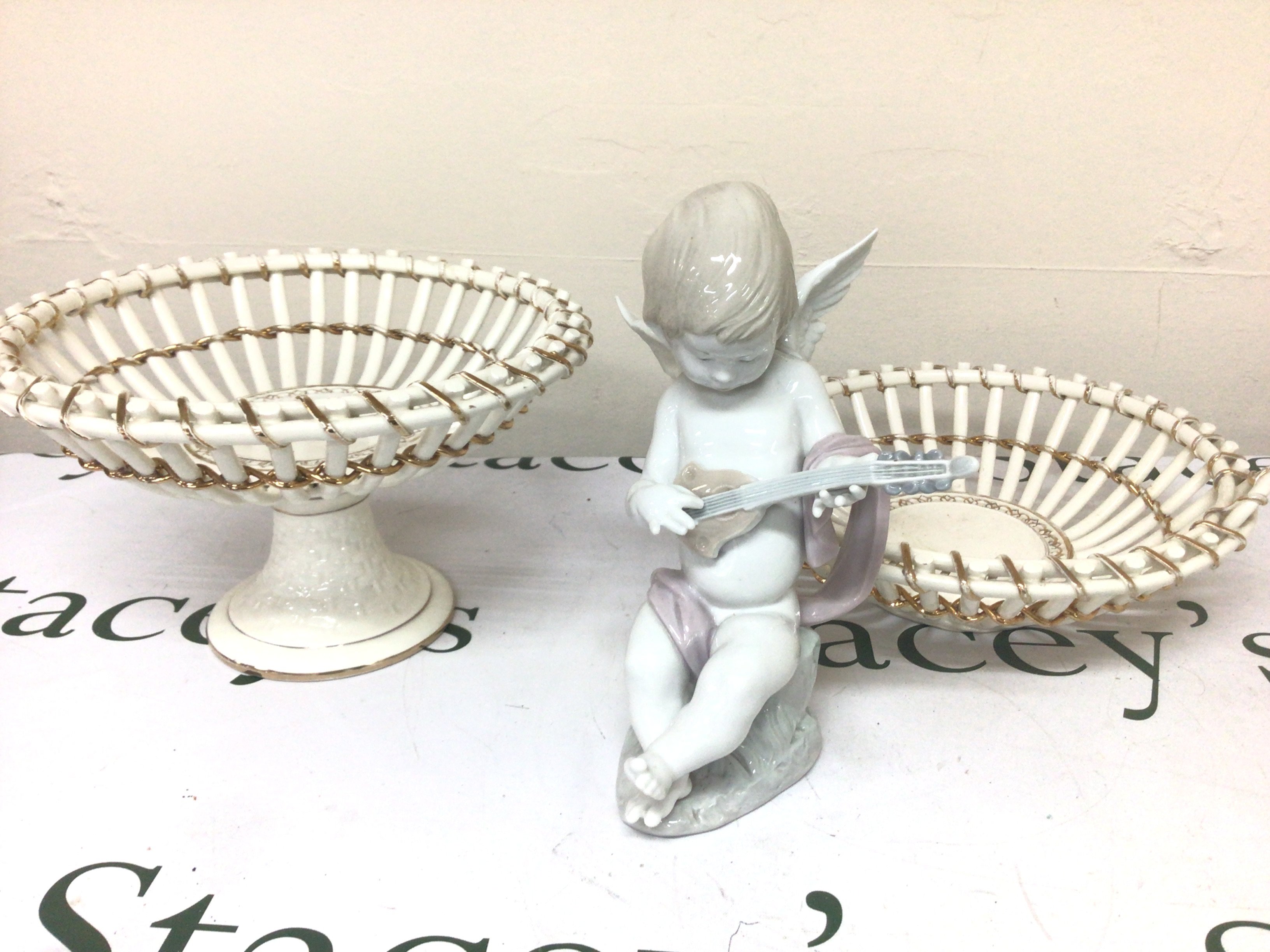 A Lladro figure of a seated cherub playing musical instrument and two white glazed open ceramic baskets no damage (3)