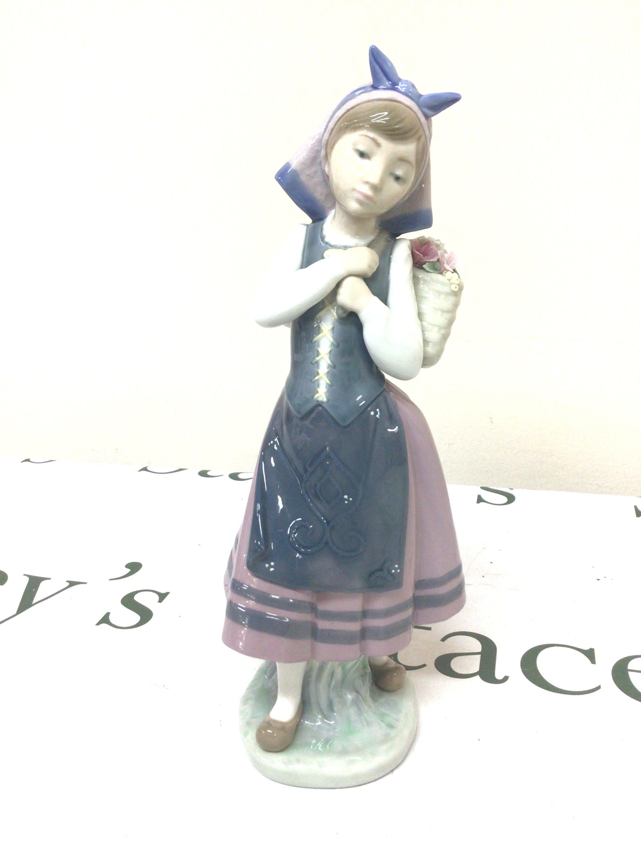 A Lladro figure of a young girl in traditional dress. No obvious damage Hight 26cm