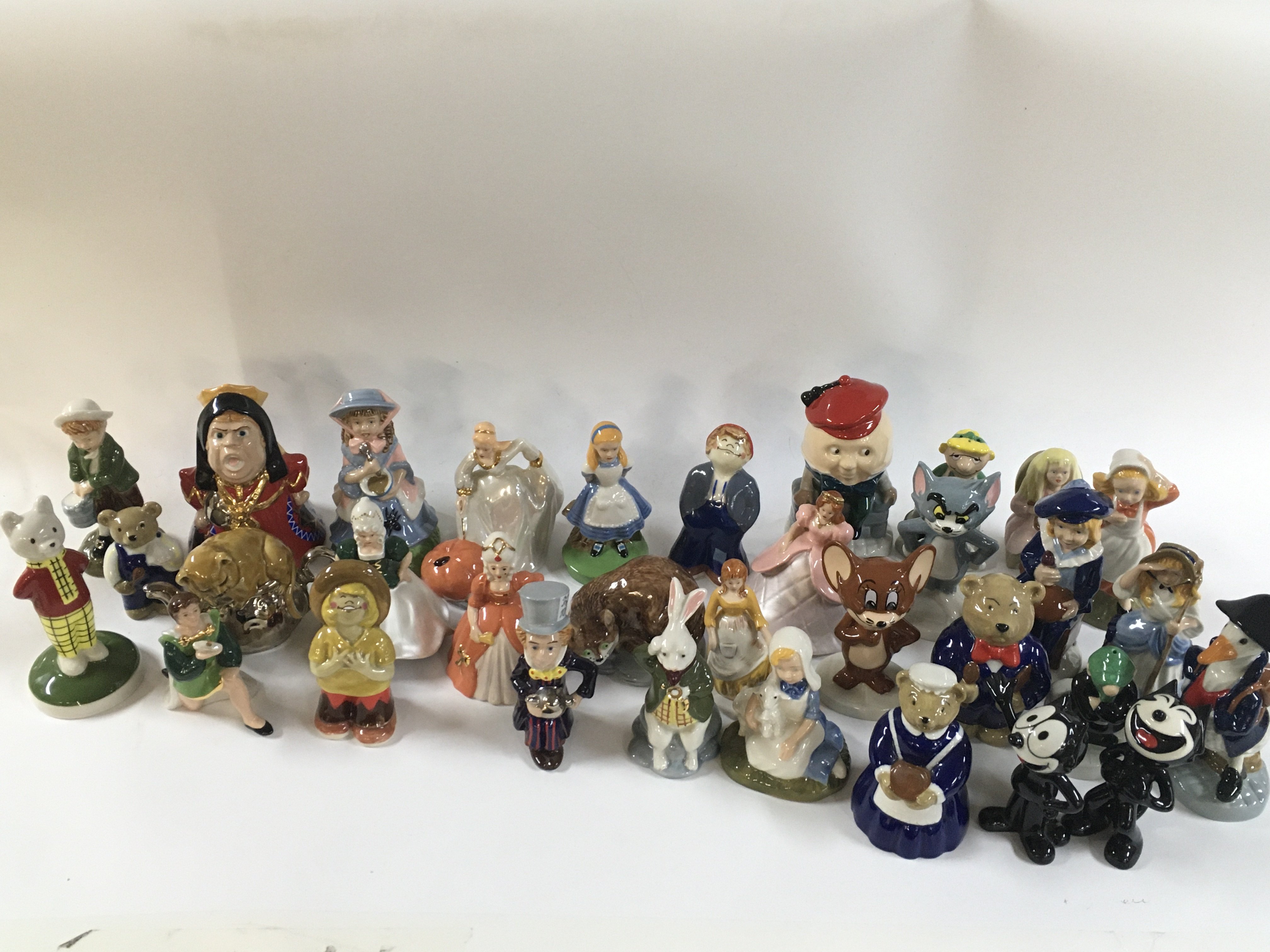 A collection of porcelain wade figures including Alice in wonderland figurines, Tom and Jerry, Felix the cat etc.
