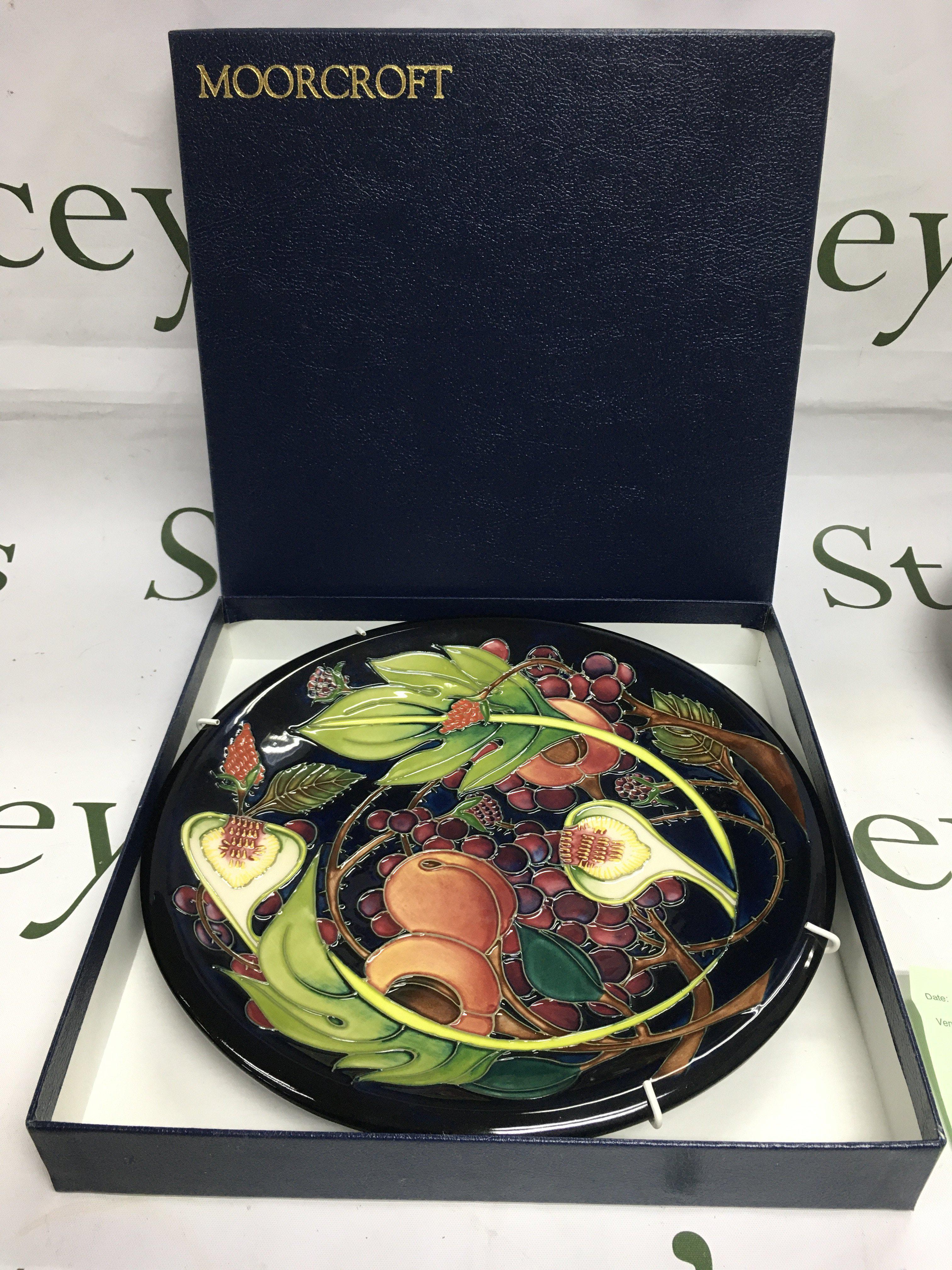 A boxed Moorcroft plate in Queen's Choice pattern, approx diameter 26cm. Shipping category D.