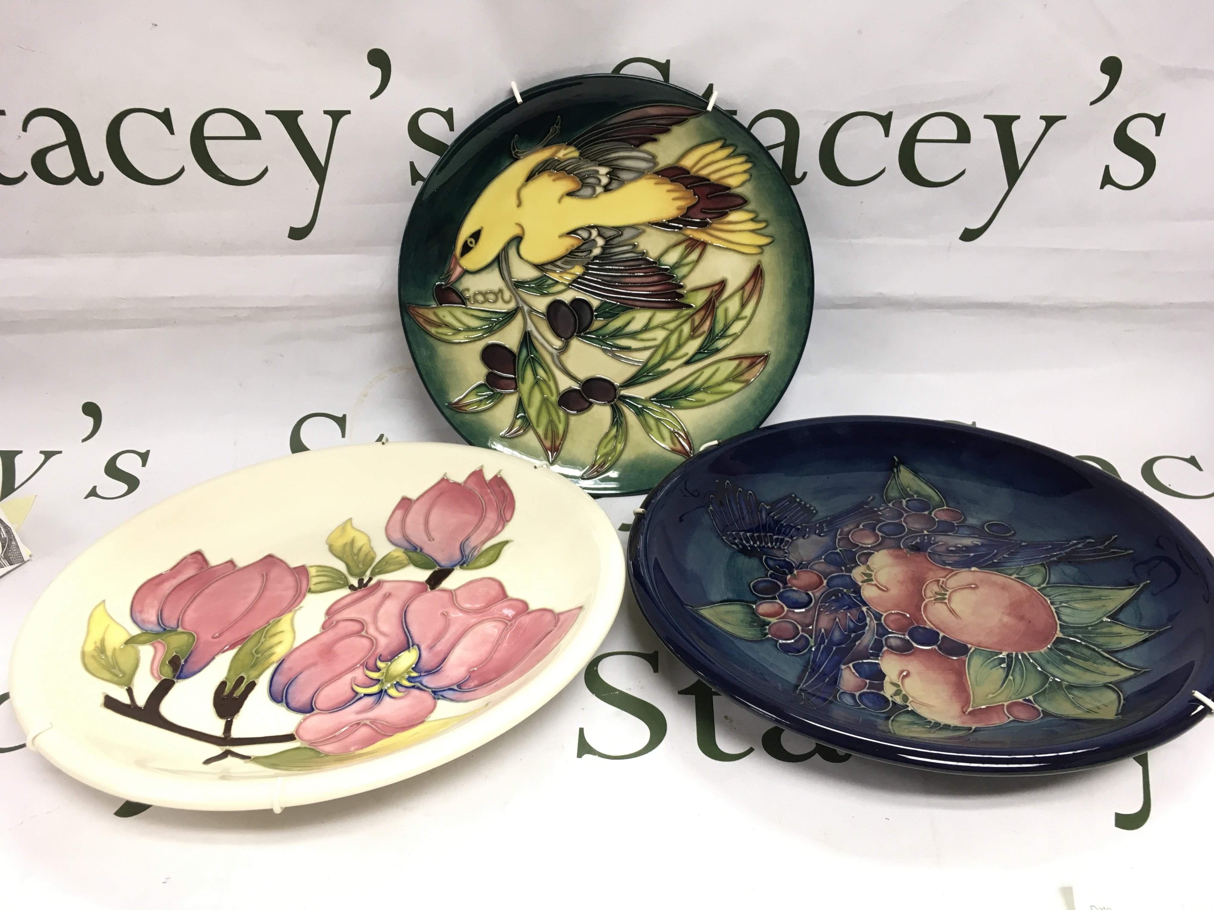 Three Moorcroft plates and a dish in various patterns comprising Golden Oriole, Magnolia and Finches, largest diameter approx 25.5cm. Shipping category D.