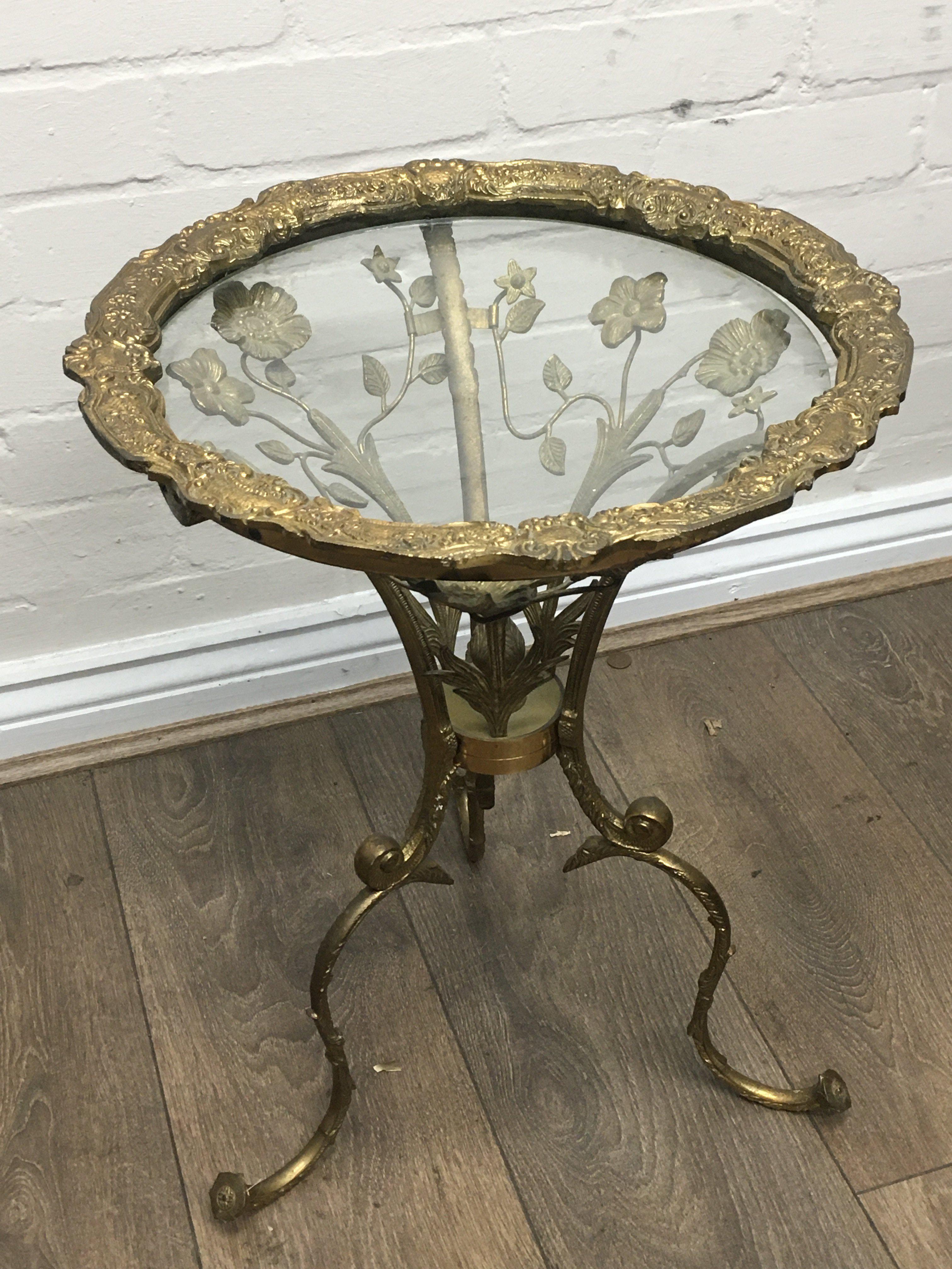 A small heavy brass glass topped table with leaf decoration. 53cm tall 39cm wide