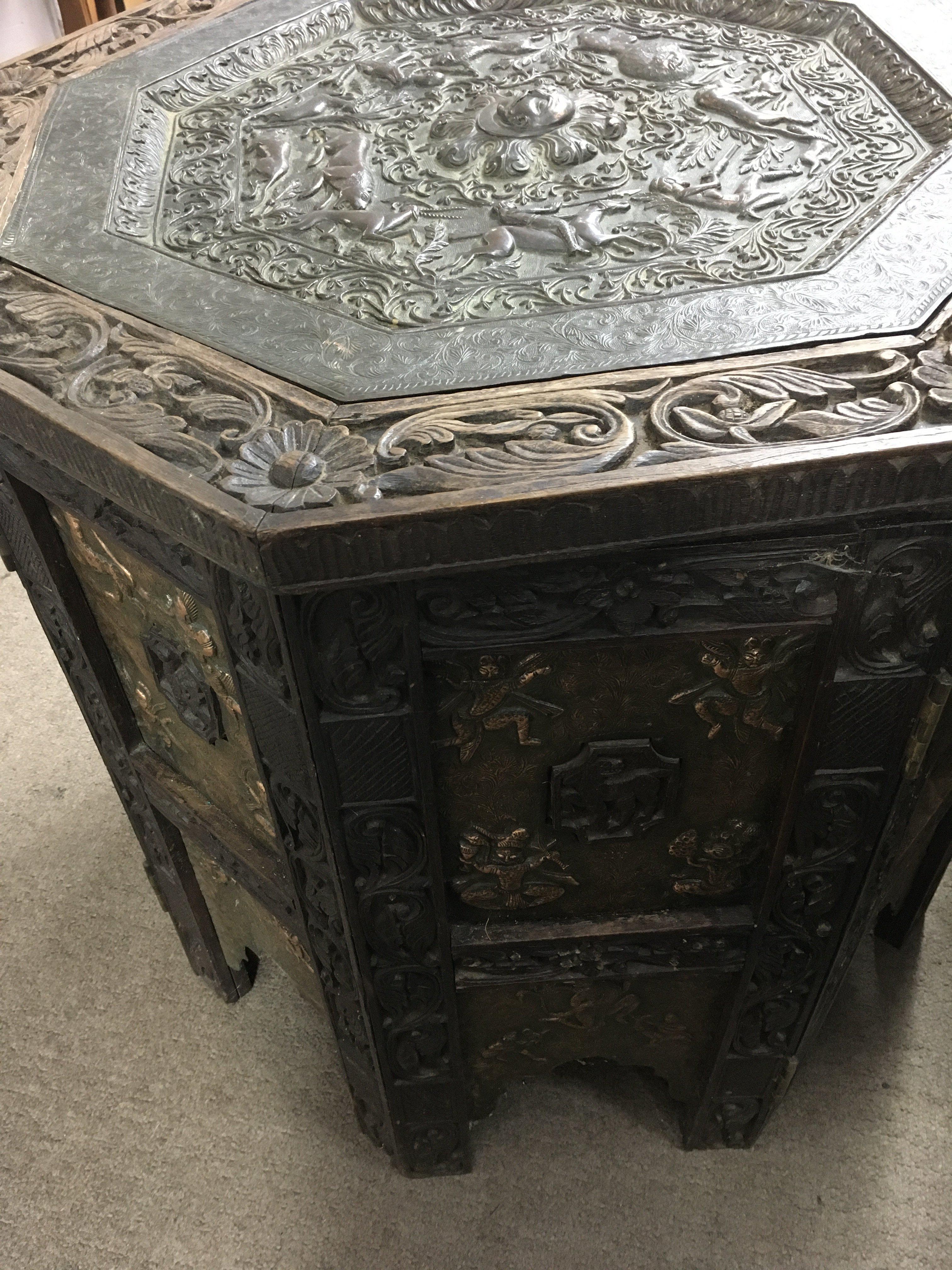 A Anglo Indian folding table with copper tray above a carved stand inset With copper panels. 70cm wide 66 high.