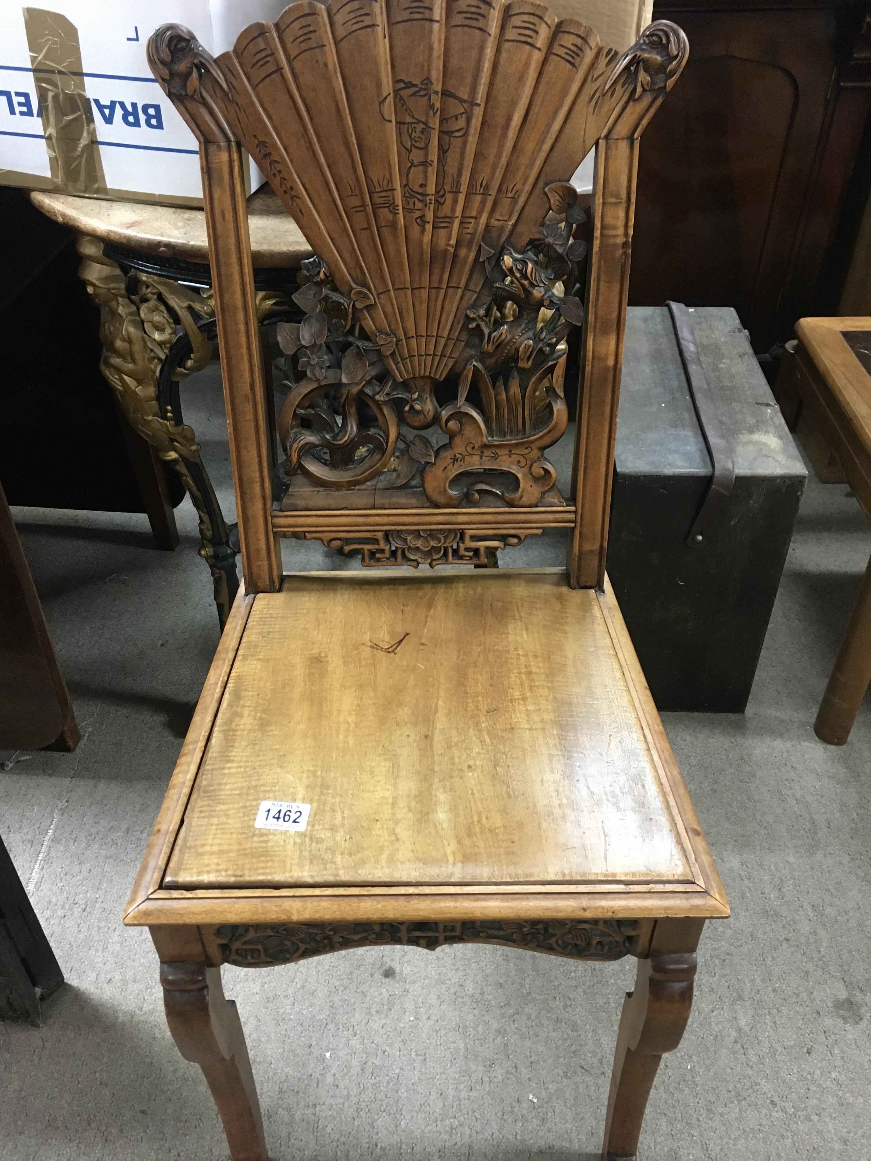 A Chinese chair the backed carved with dragons flowers and a fan above a drop in seat on scrolled Legs .