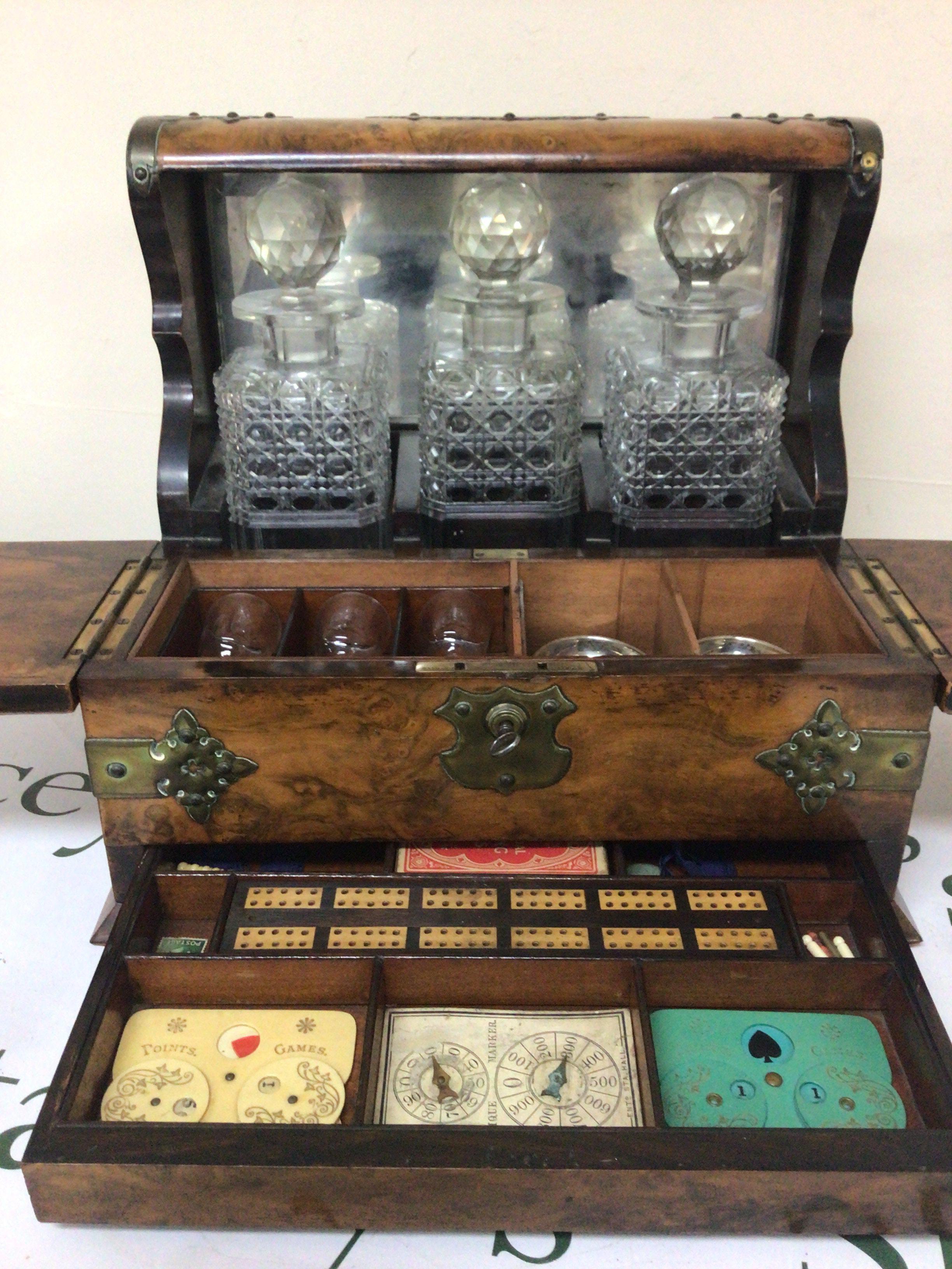 A late Victorian burr walnut tantalus with three bottles key and fitted interior brass mounts. The interior with small glasses and games compendium.