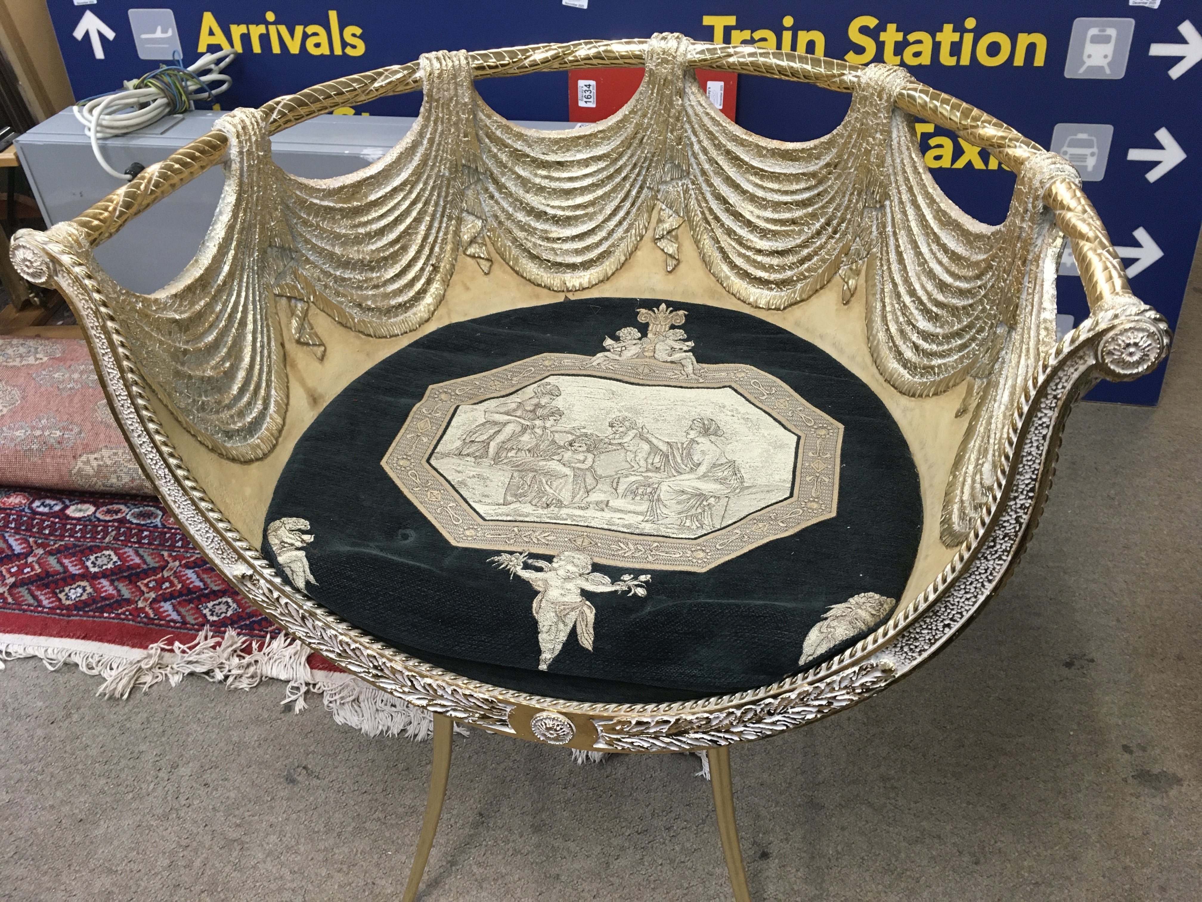 This is a gilt, neoclassical-style chair with a dark velvet cushion and putti details. 70cm tall 67cm wide