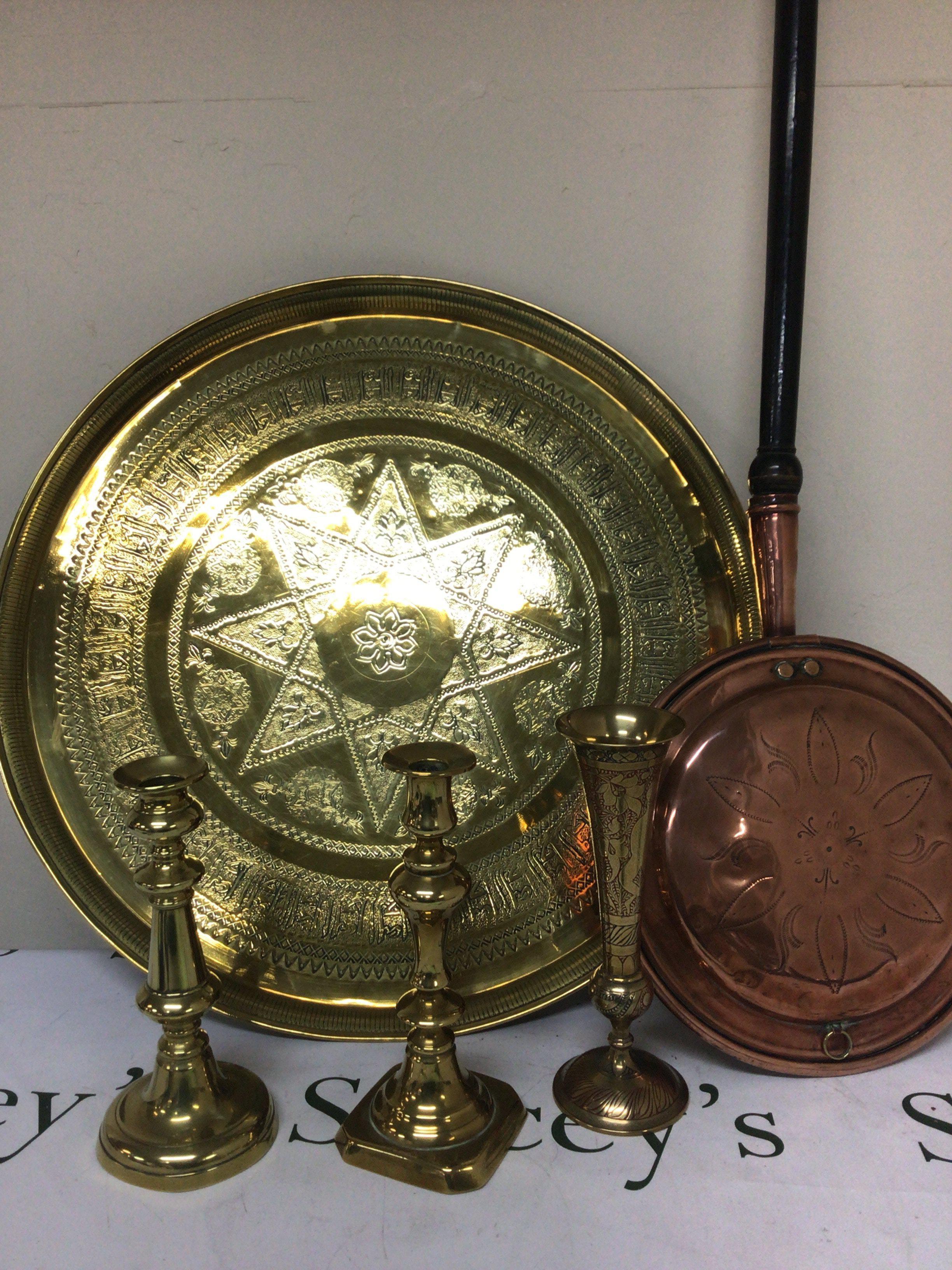 A pair of brass candle sticks a large brass tray and a copper warming pan.