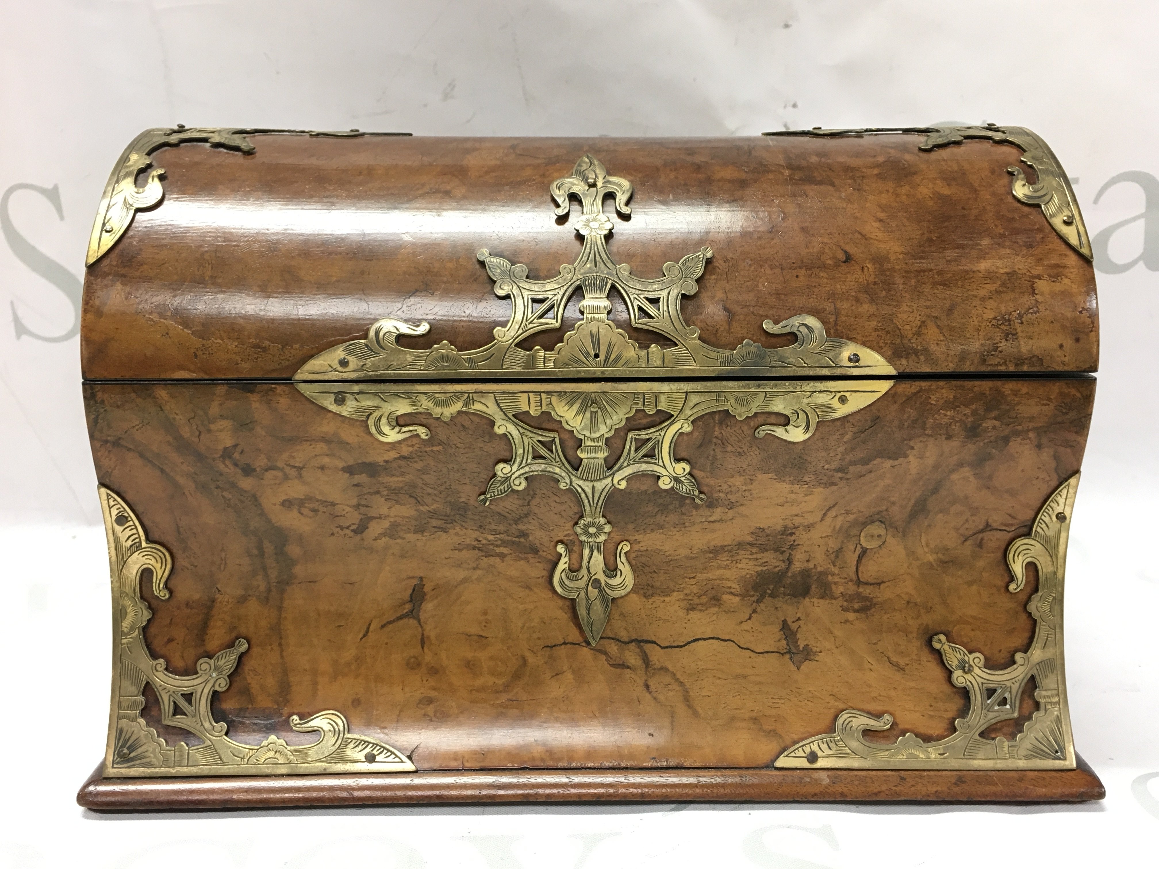 A walnut dome topped stationary box with ornate engraved brass mounts. 24cm wide 16cm tall