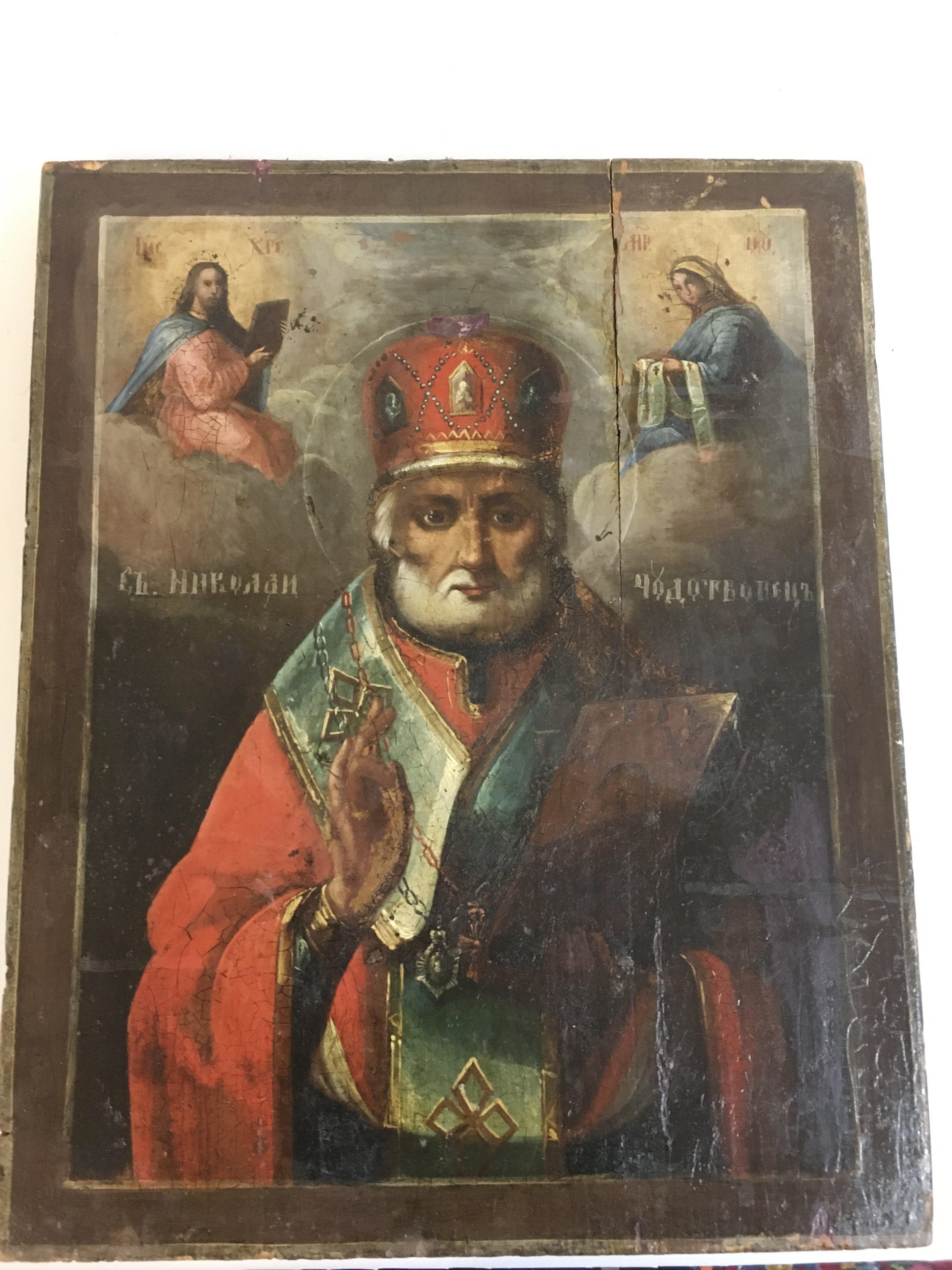 A 19th century Russian icon depicting Saint Nicholas of Myra , oil on wood, flanked by Christ and the mother of God with inscriptions 28.5cm wide 35cm tall approximately . Postage catC