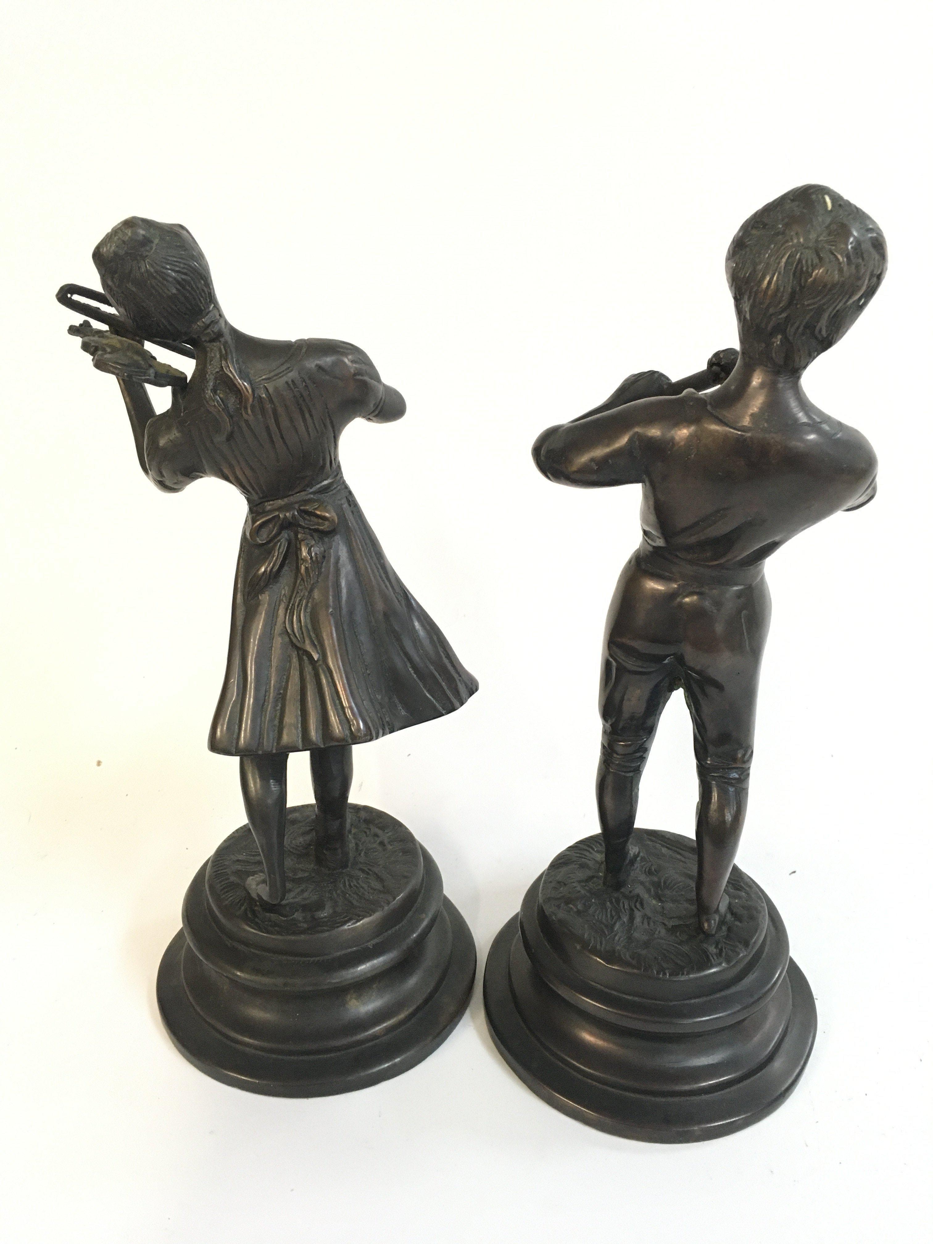 A bronze pair of figures a girl playing a violin and boy with flute , 25cm tall. Postage category c