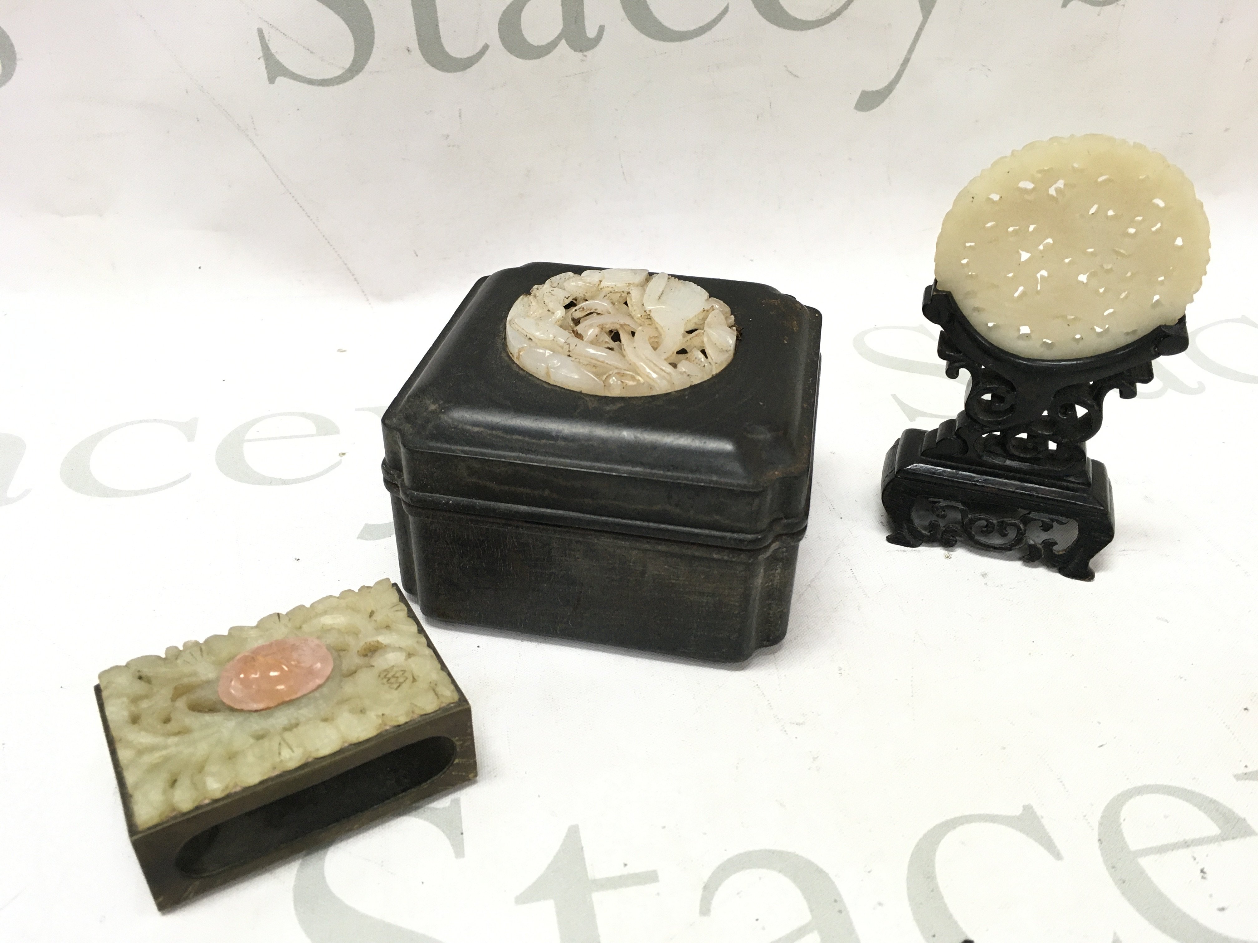 Chinese Jade items including a matchbox holder, trinket box and an ornament on a wooden stand. Postage category B