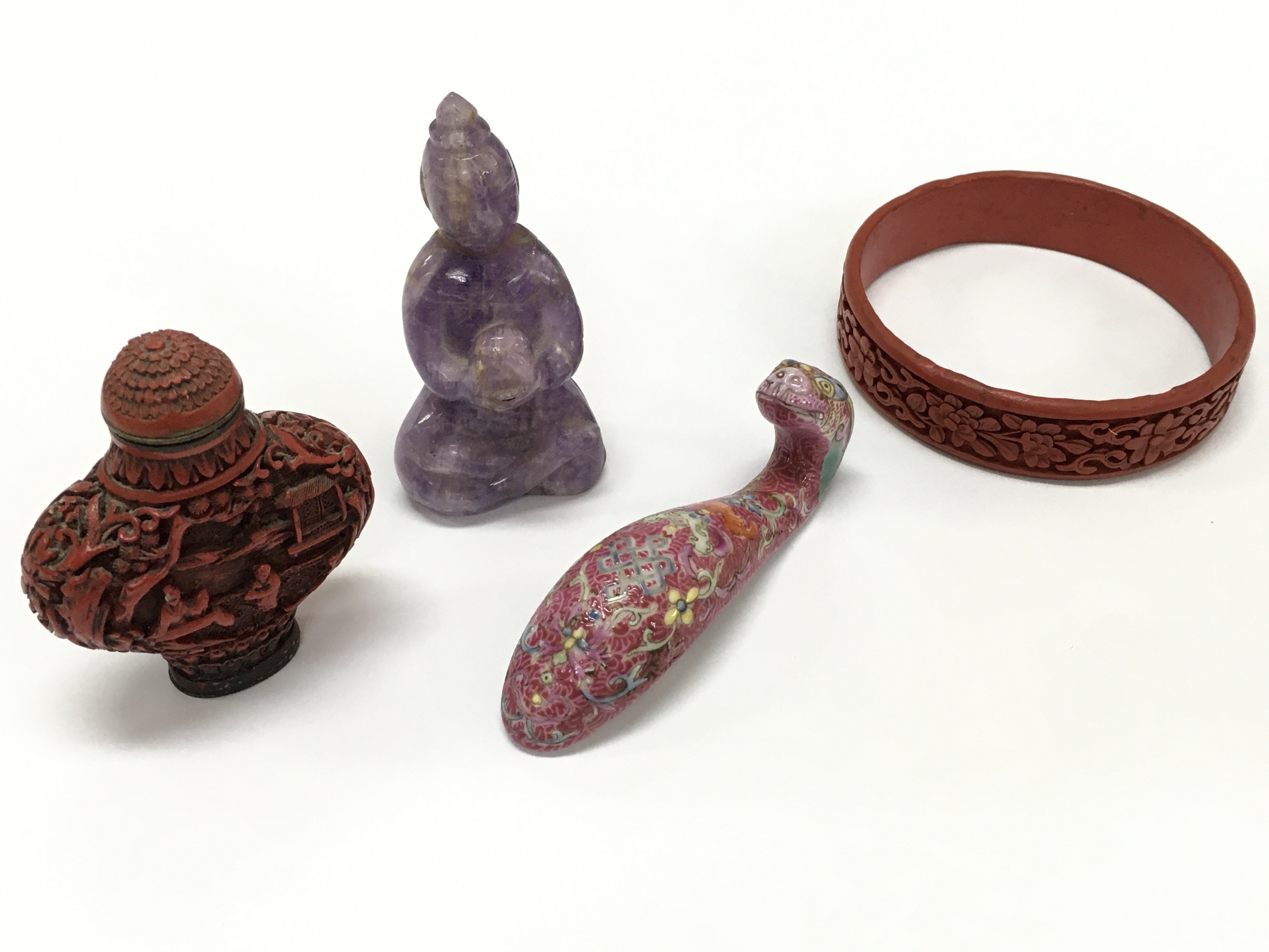 Chinese items including a red snuff bottle , carved gemstone Buddha figure , ceramic dragon head, red bangle style bracelet with a carved floral pattern. This lot cannot be posted