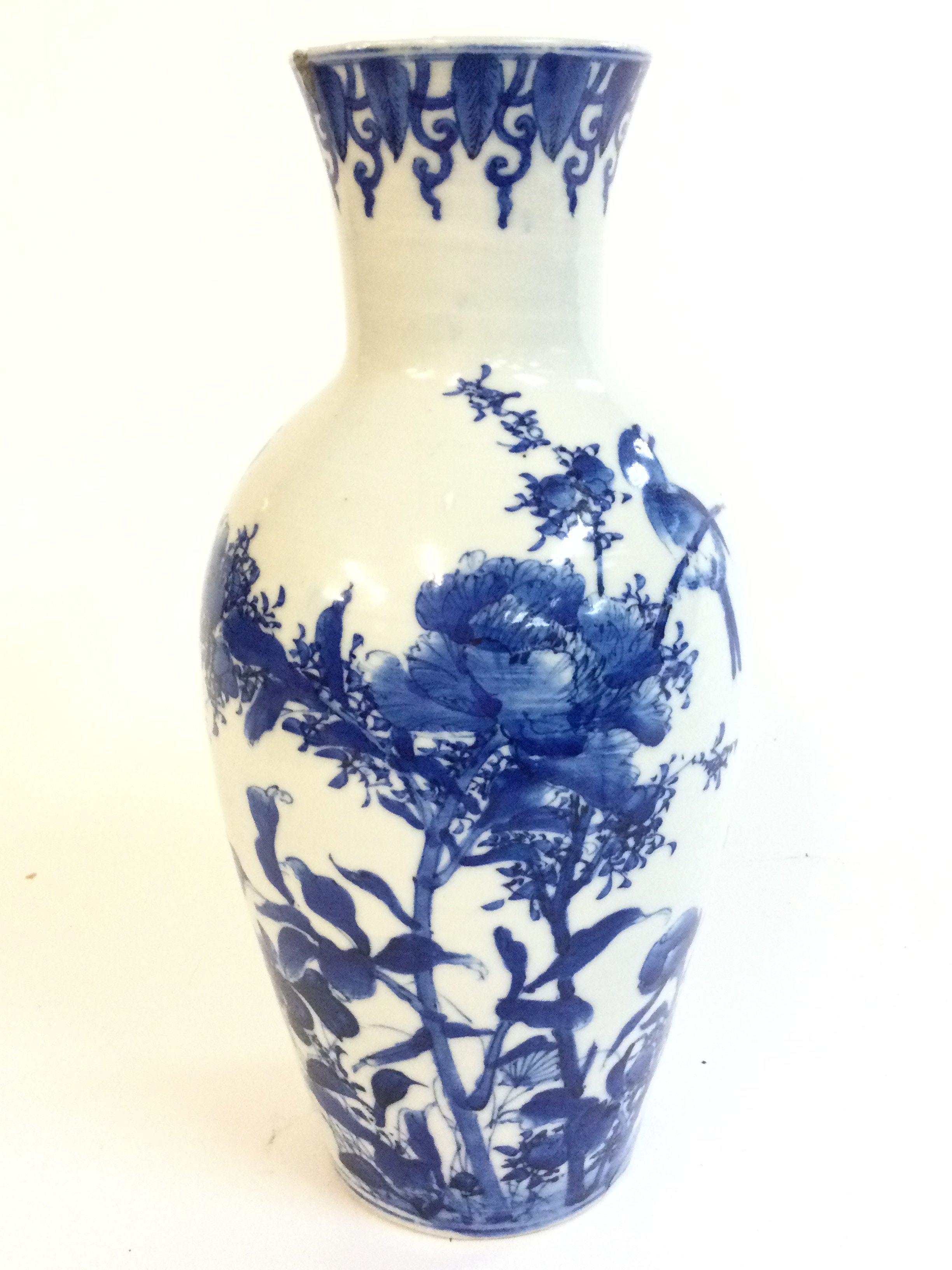 A Chinese blue and white porcelain vase depicting a bird perched on flowering plants (rim of vase damaged with chip and hairline crack and crack at base) 25cm tall.