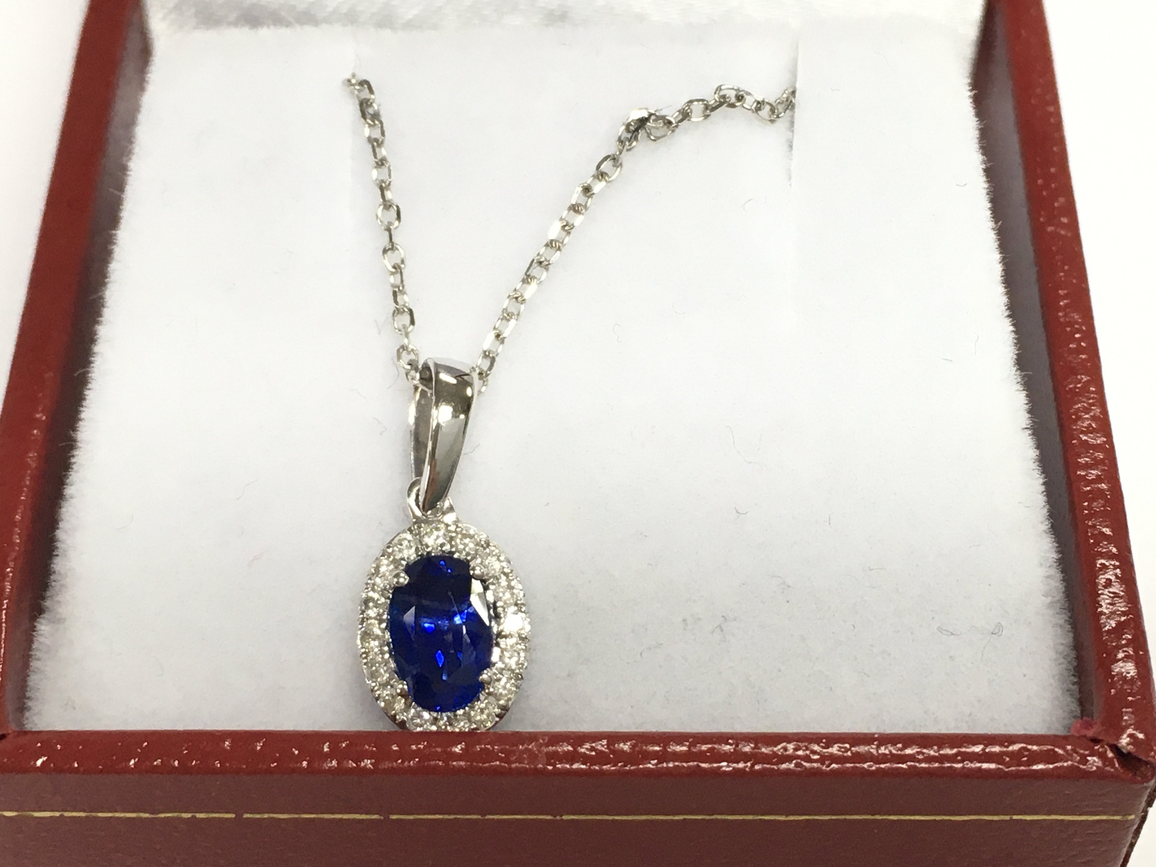 18ct white gold sapphire and diamond cluster pendant on an 18ct white gold chain. Sapphire 0.59ct and diamonds 0.10ct.