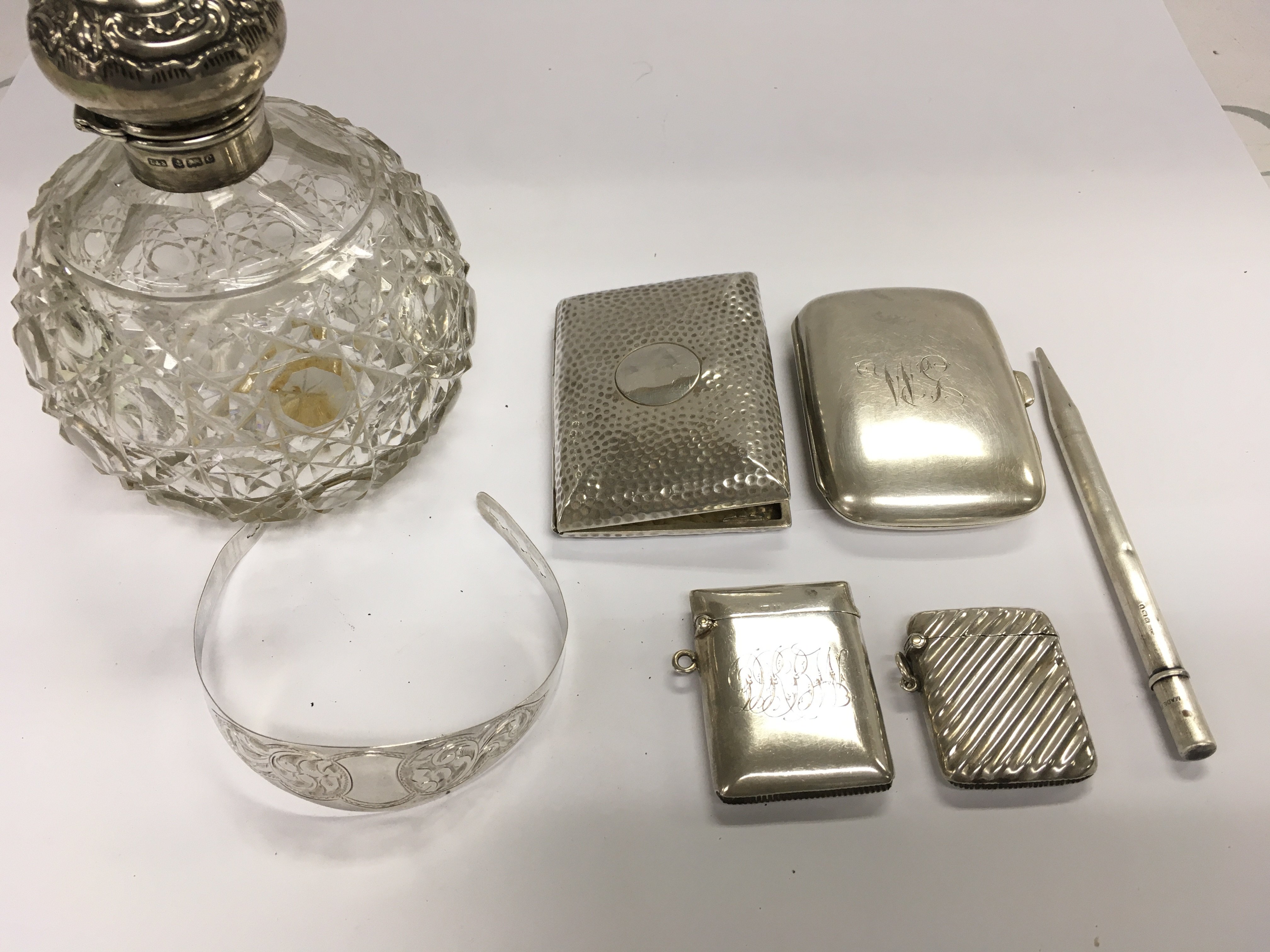 A collection of assorted silver items including silver topped scent bottle cigarette cases Vesta cases silver bracelet and a silver pencil.