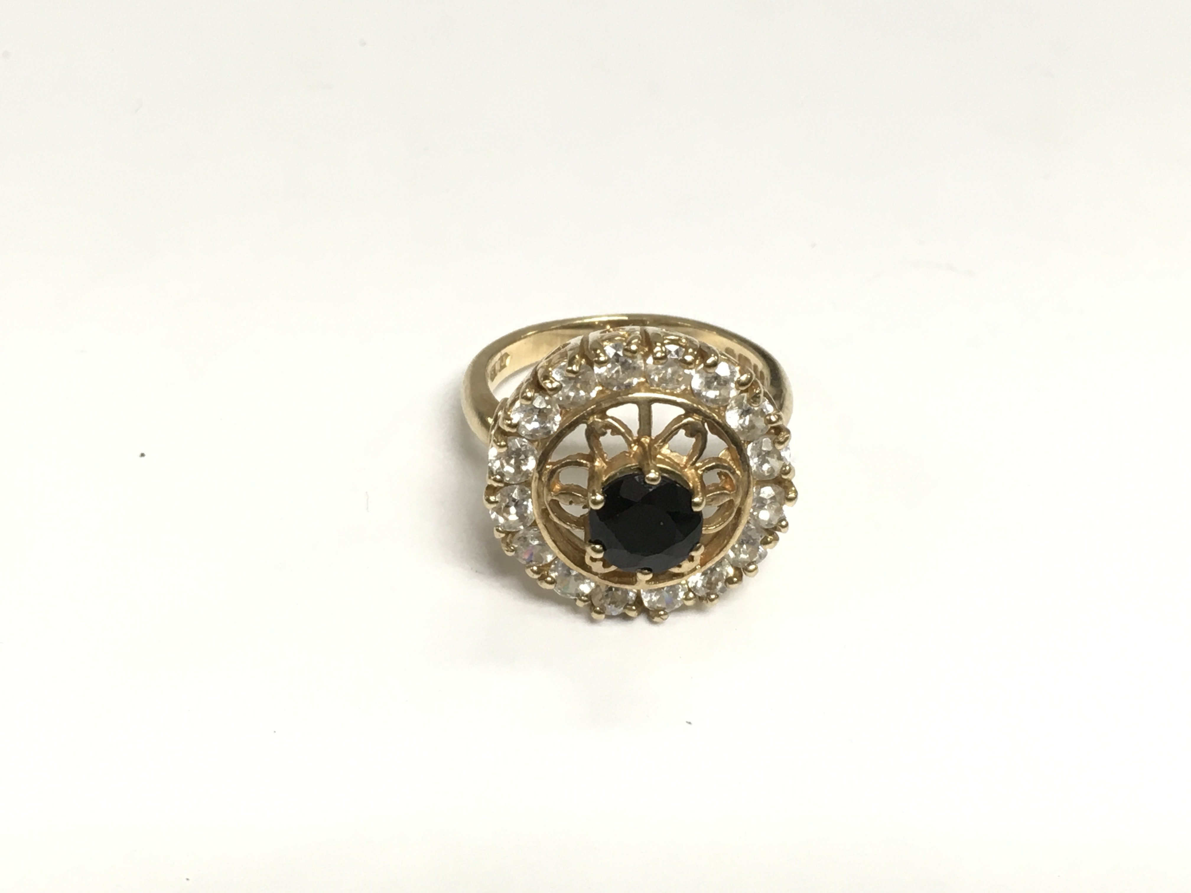 A 9ct gold ring set with a central sapphire surrounded by a halo of clear stones, approx 5.8g and approx size N. Shipping category A.