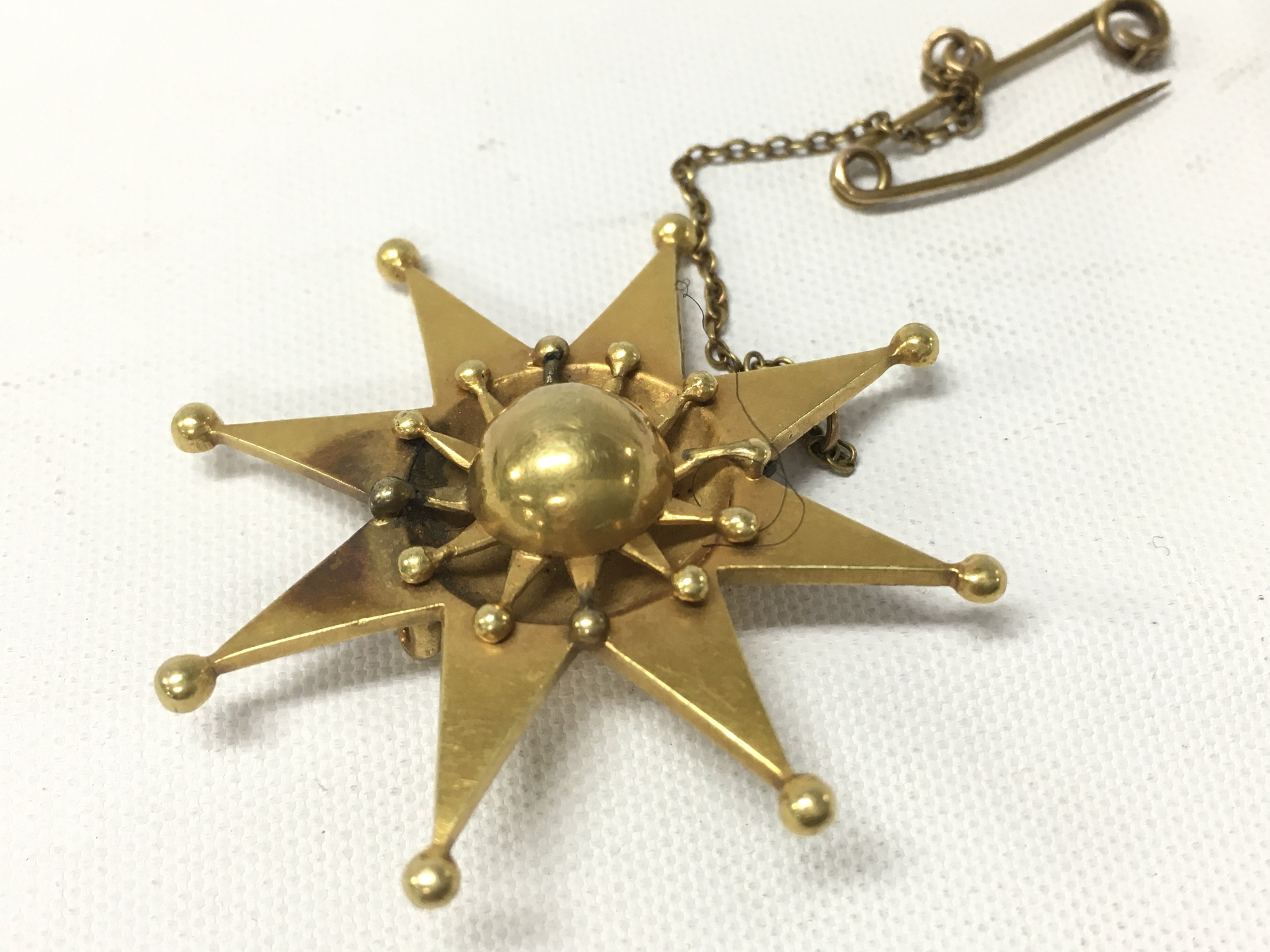 A yellow metal unmarked star brooch. Approx weight 8.63 grams.