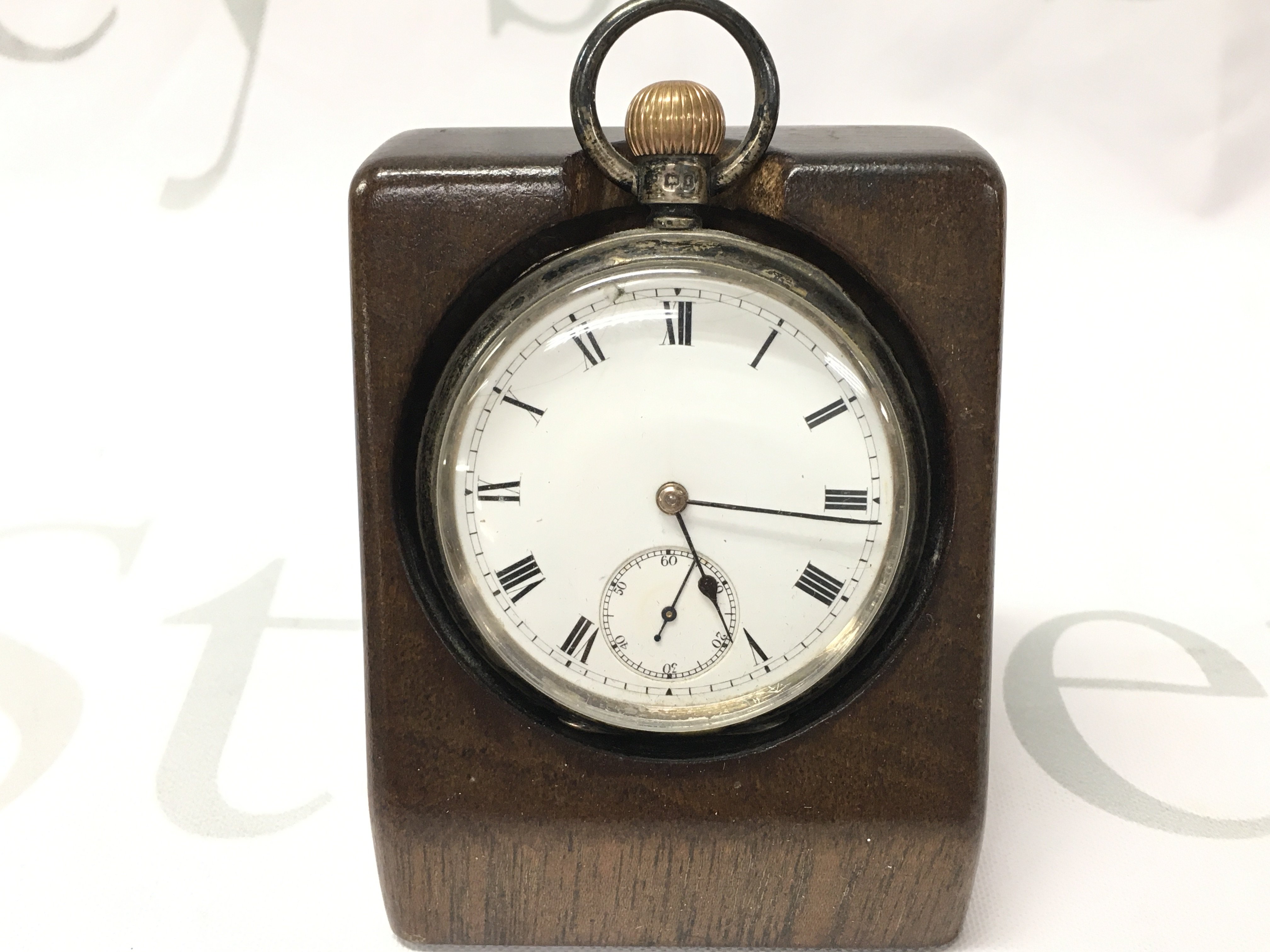 A hallmarked silver Waltham pocket watch with a wooden stand.