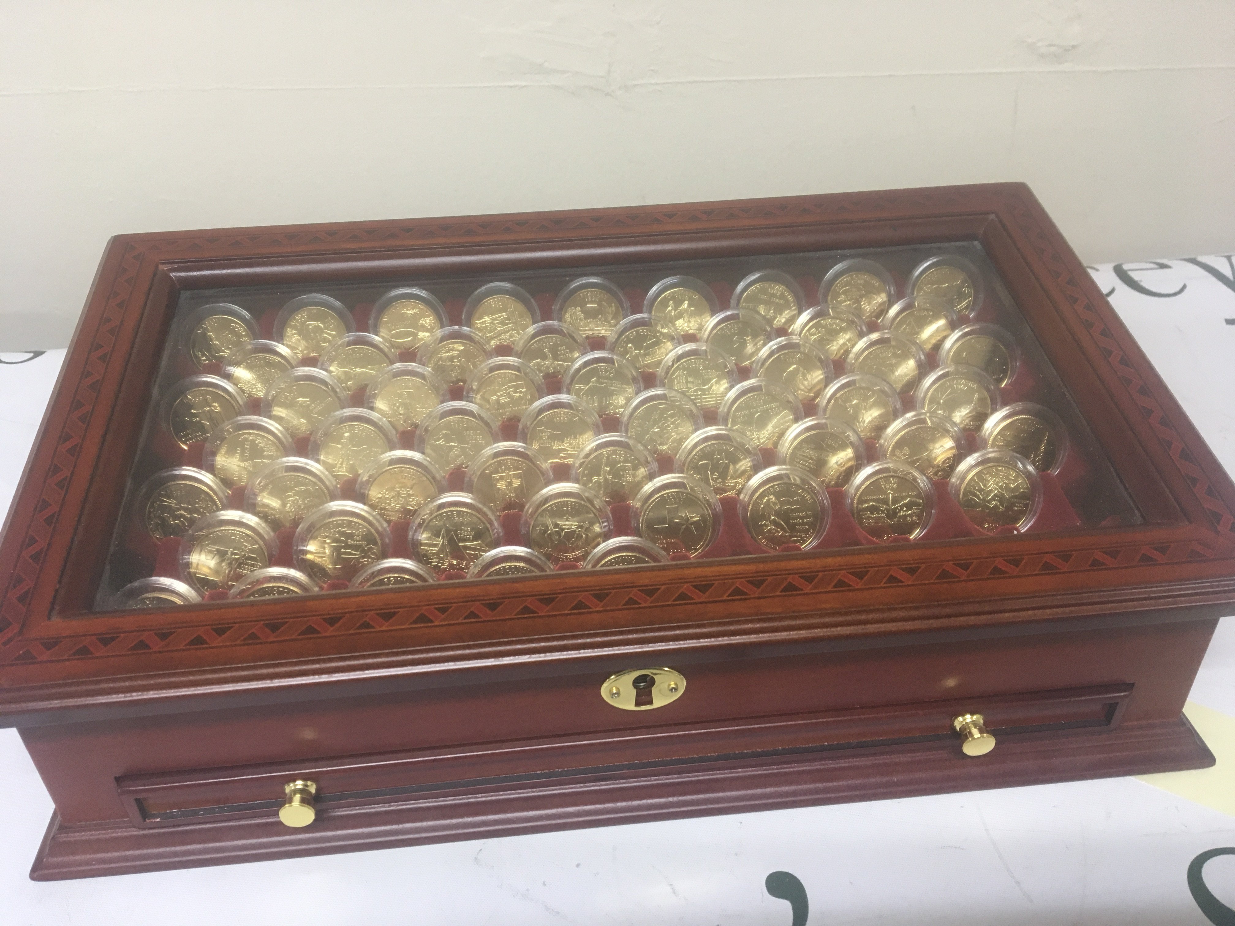 A case containing a collection of American gilded Quarter Dollars virtually complete each coin in a sealed capsule uncirculated and in a well presented fitted case.