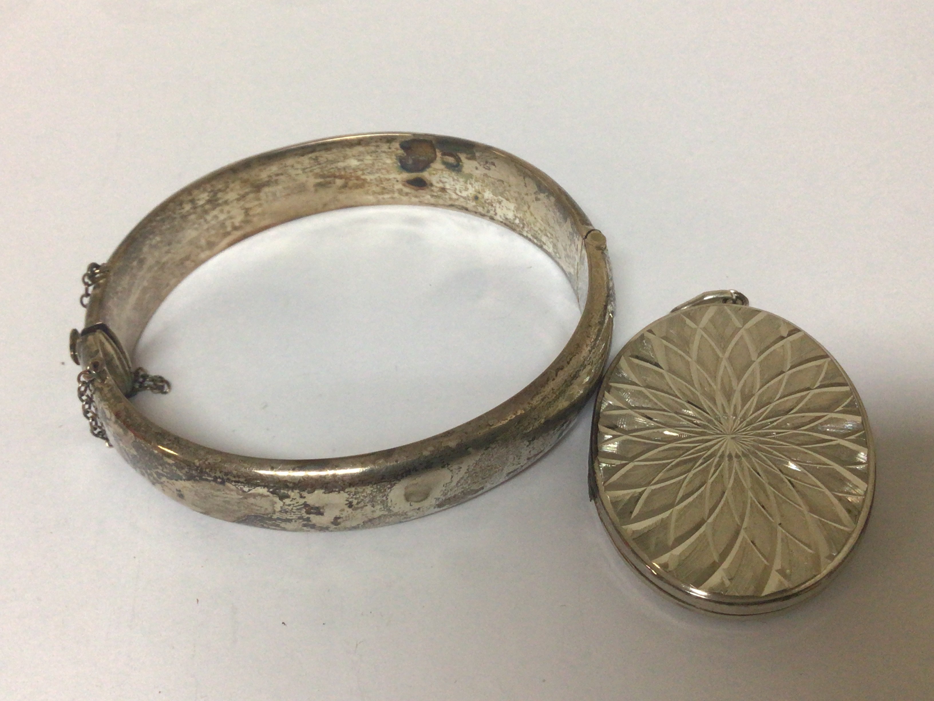 A Silver bangle and an oval Silver locket. (2)