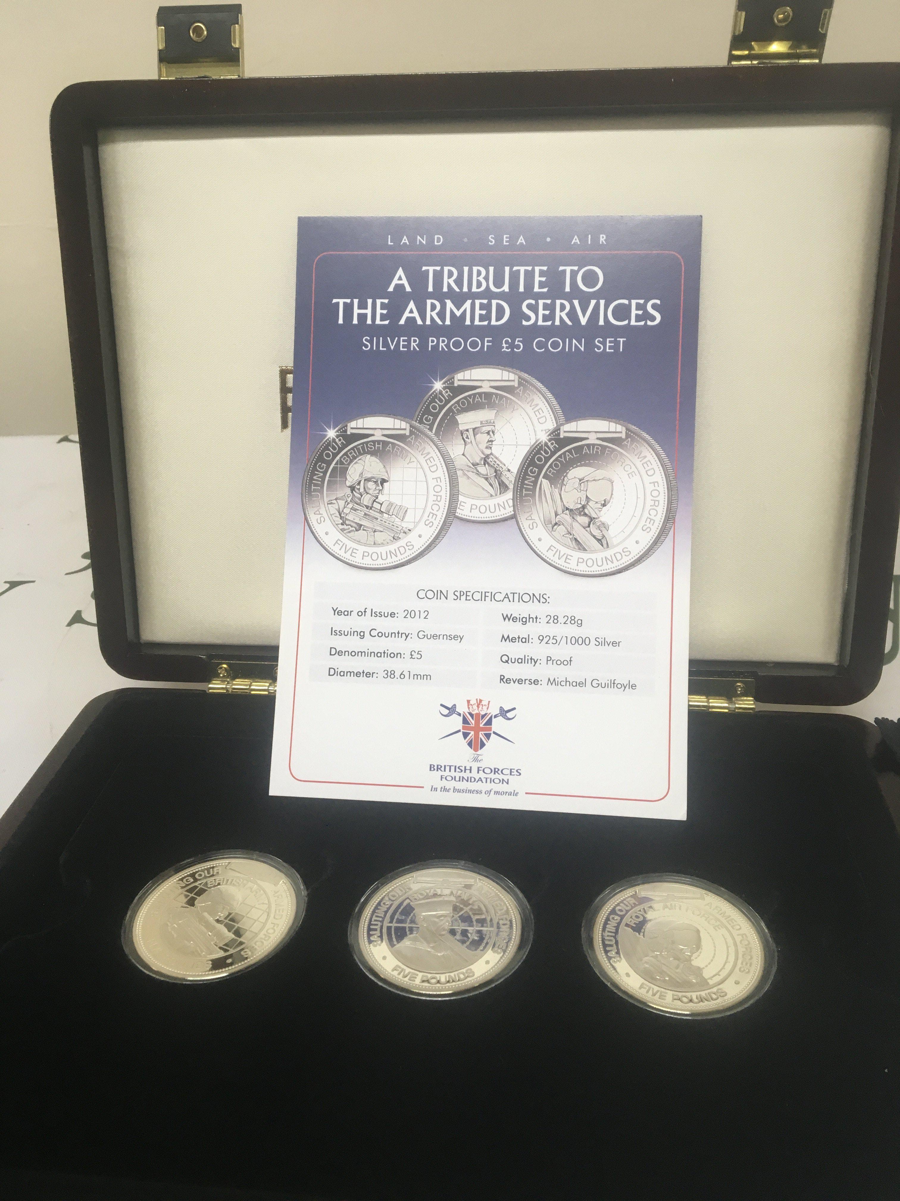 A cased Silver Proof five pound coin set A Tribute to the Armed Services. Three silver coins with certificates of authenticity.