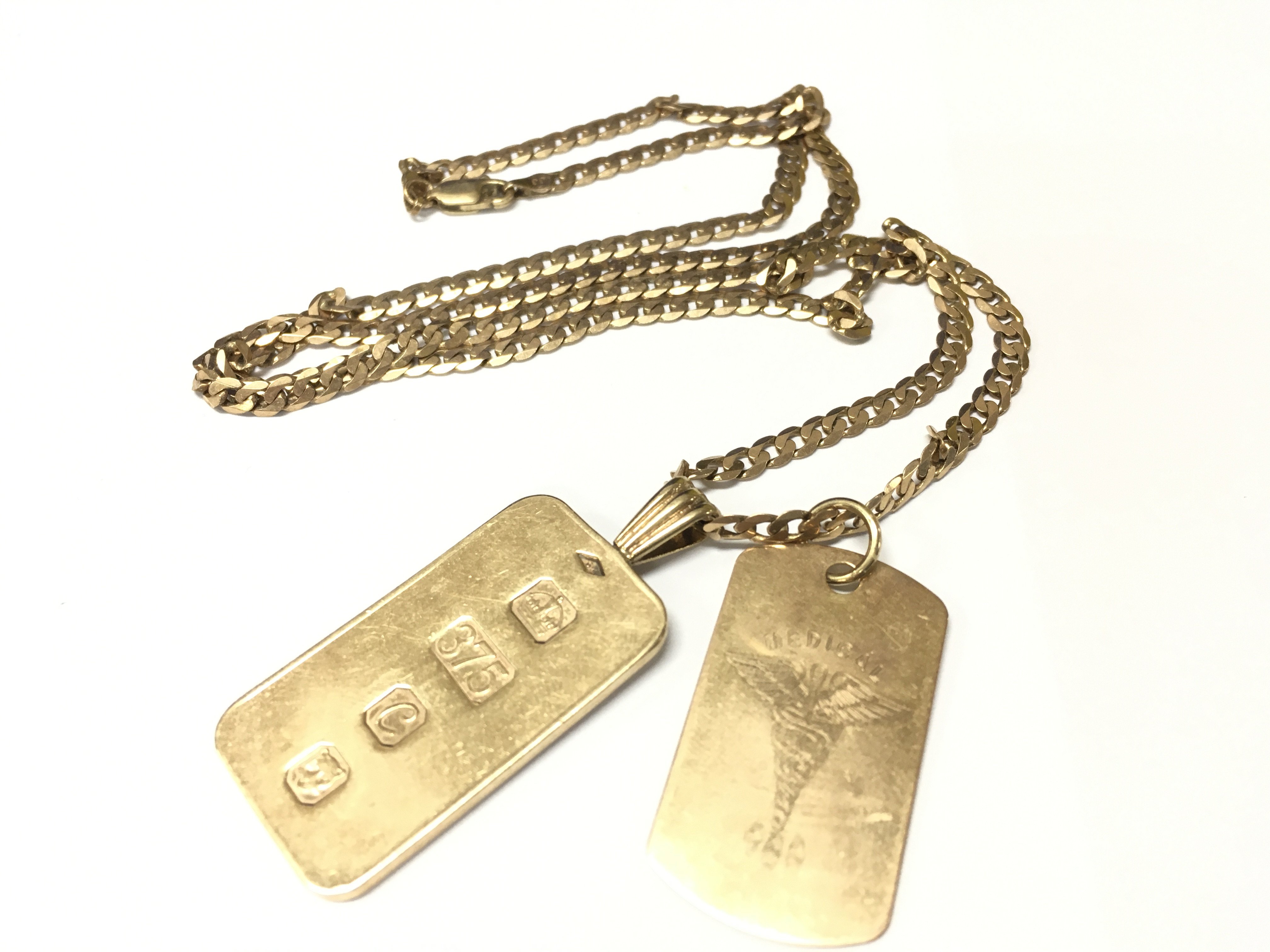 A 9ct gold ingot and medical pendant on a gold curb chain. Approx weight 29.34 grams.