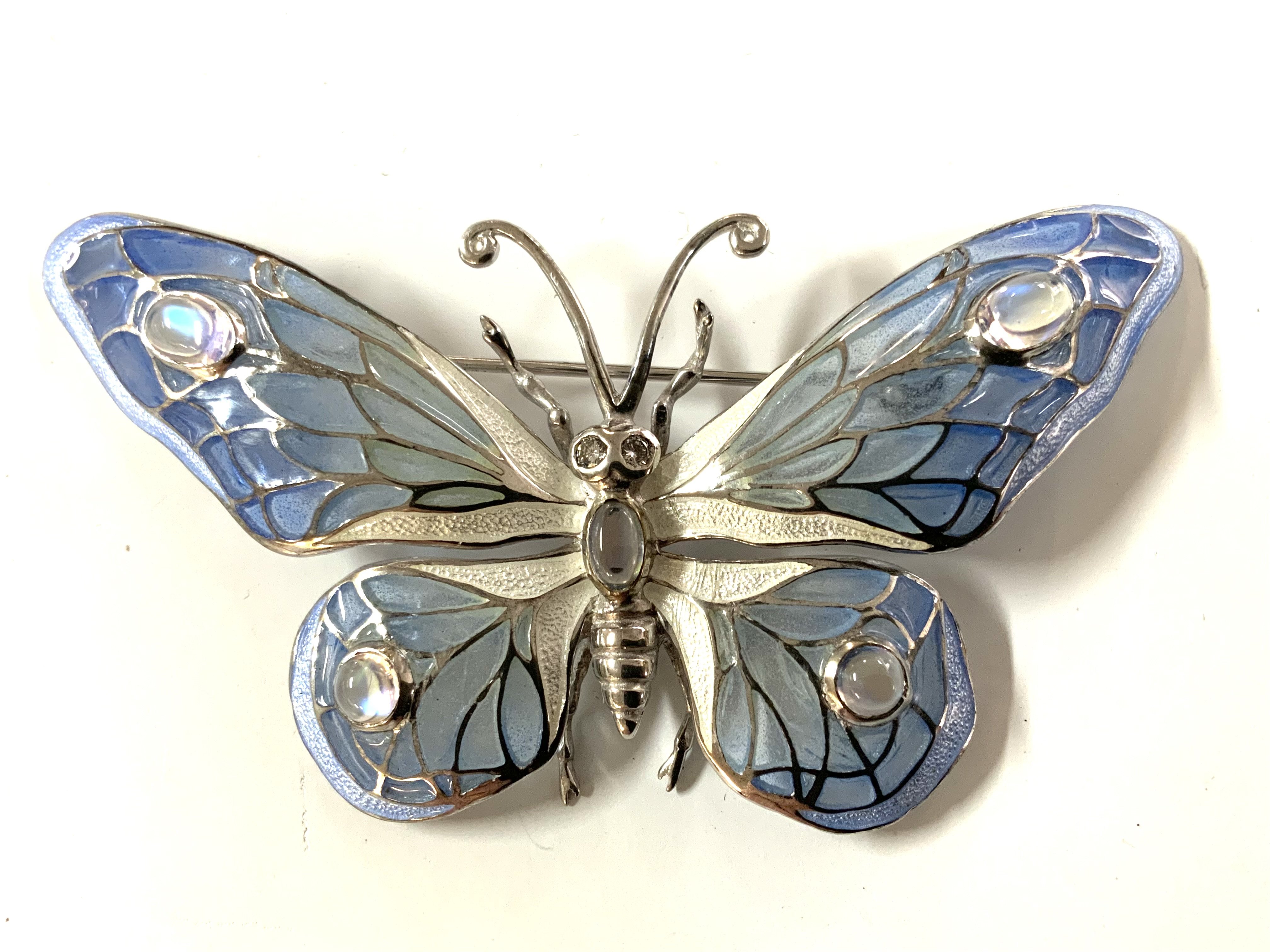 A sterling silver butterfly brooch set with moonstone and pliqe au jour enamel.