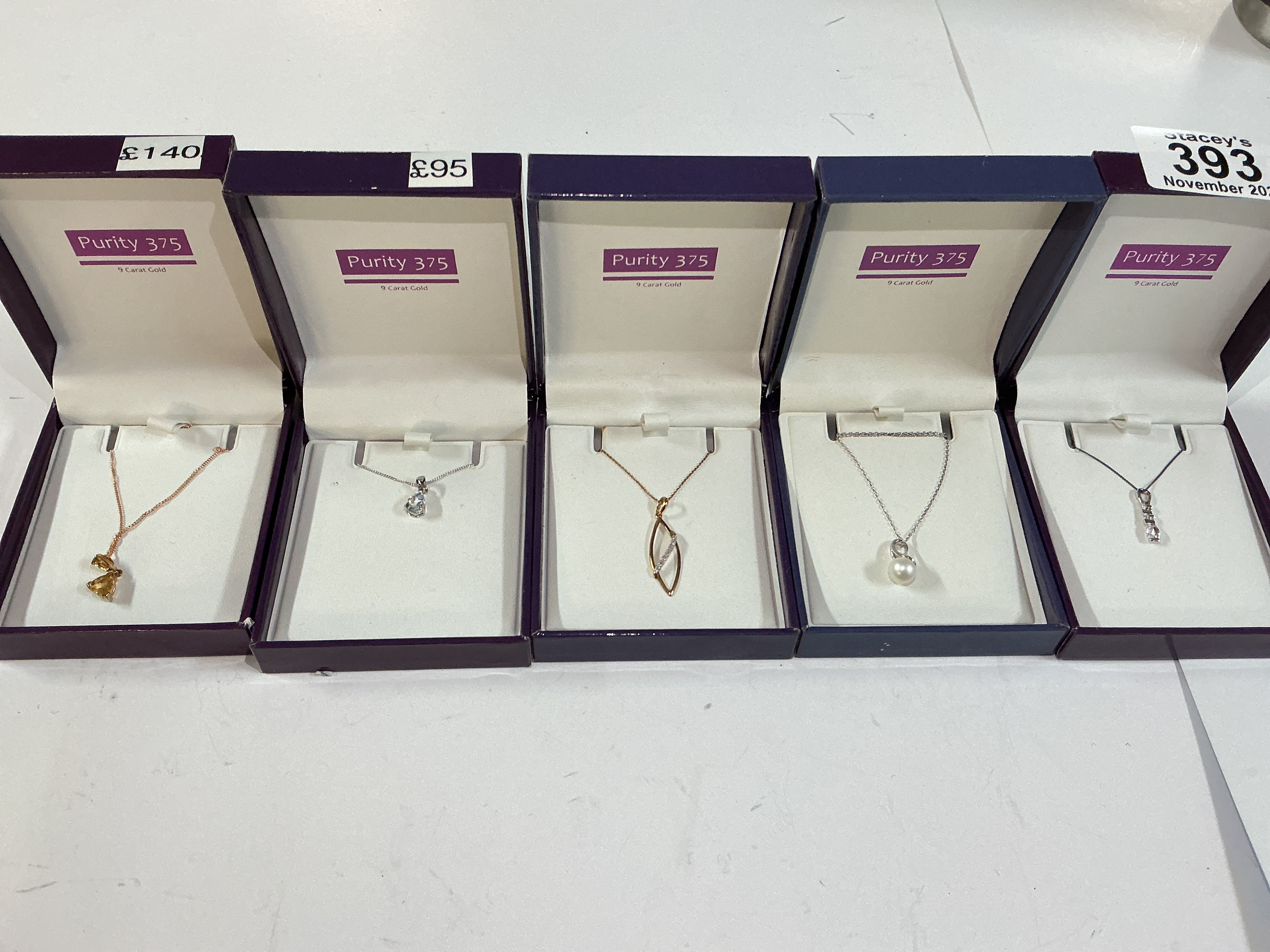Five 9ct gold (purity 375) chains with stone set pendants.