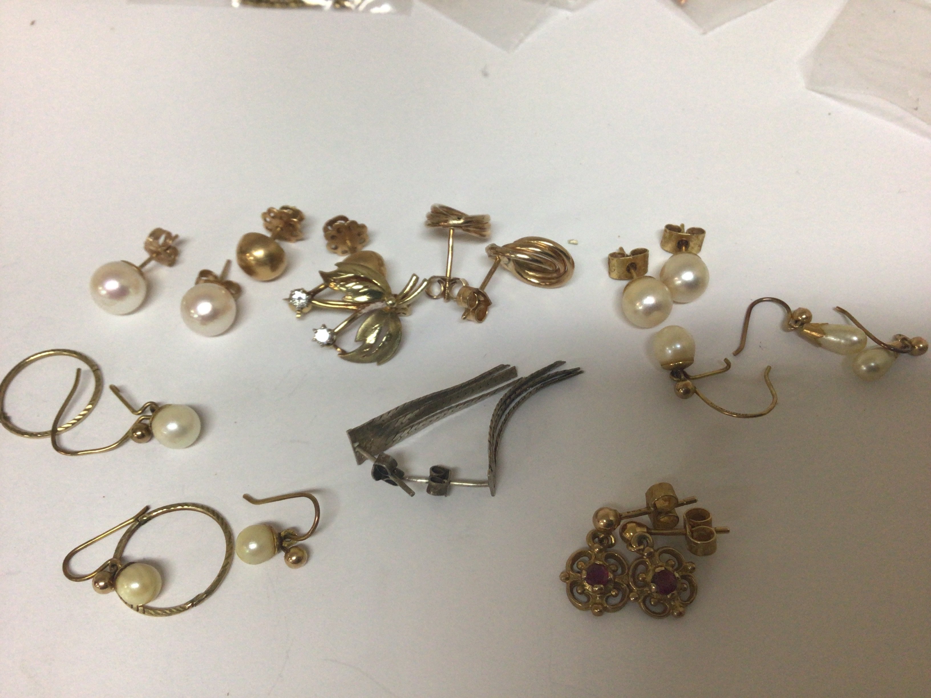 A gold brooch of floral design set with two small diamonds pearl earrings and other gold earrings.