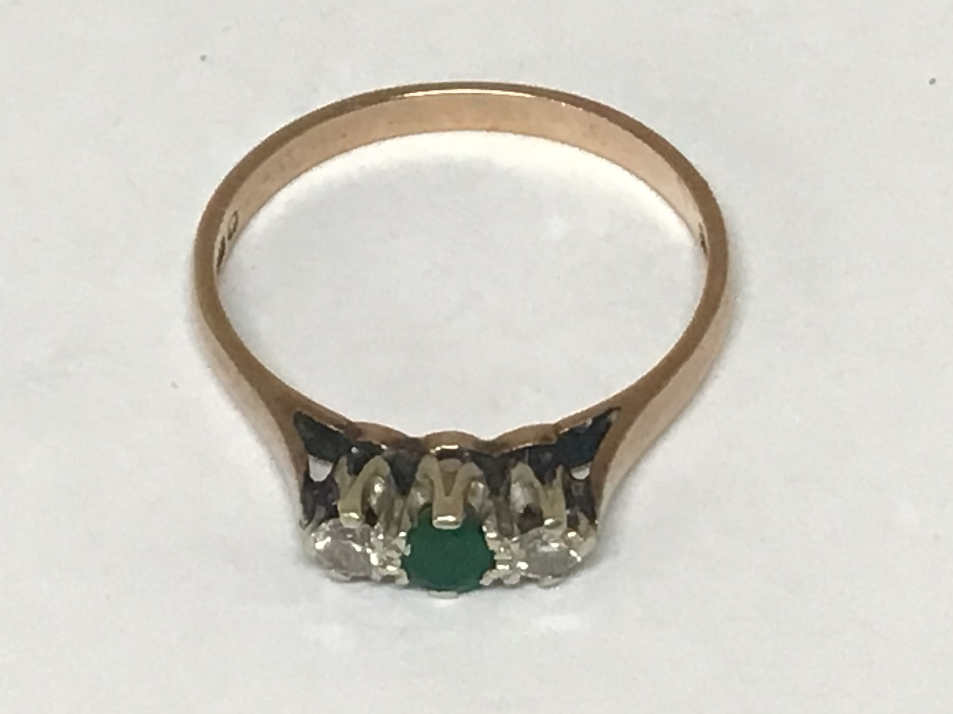 A 9carat gold ring set with an emerald flanked by chip diamonds weight 1.8g