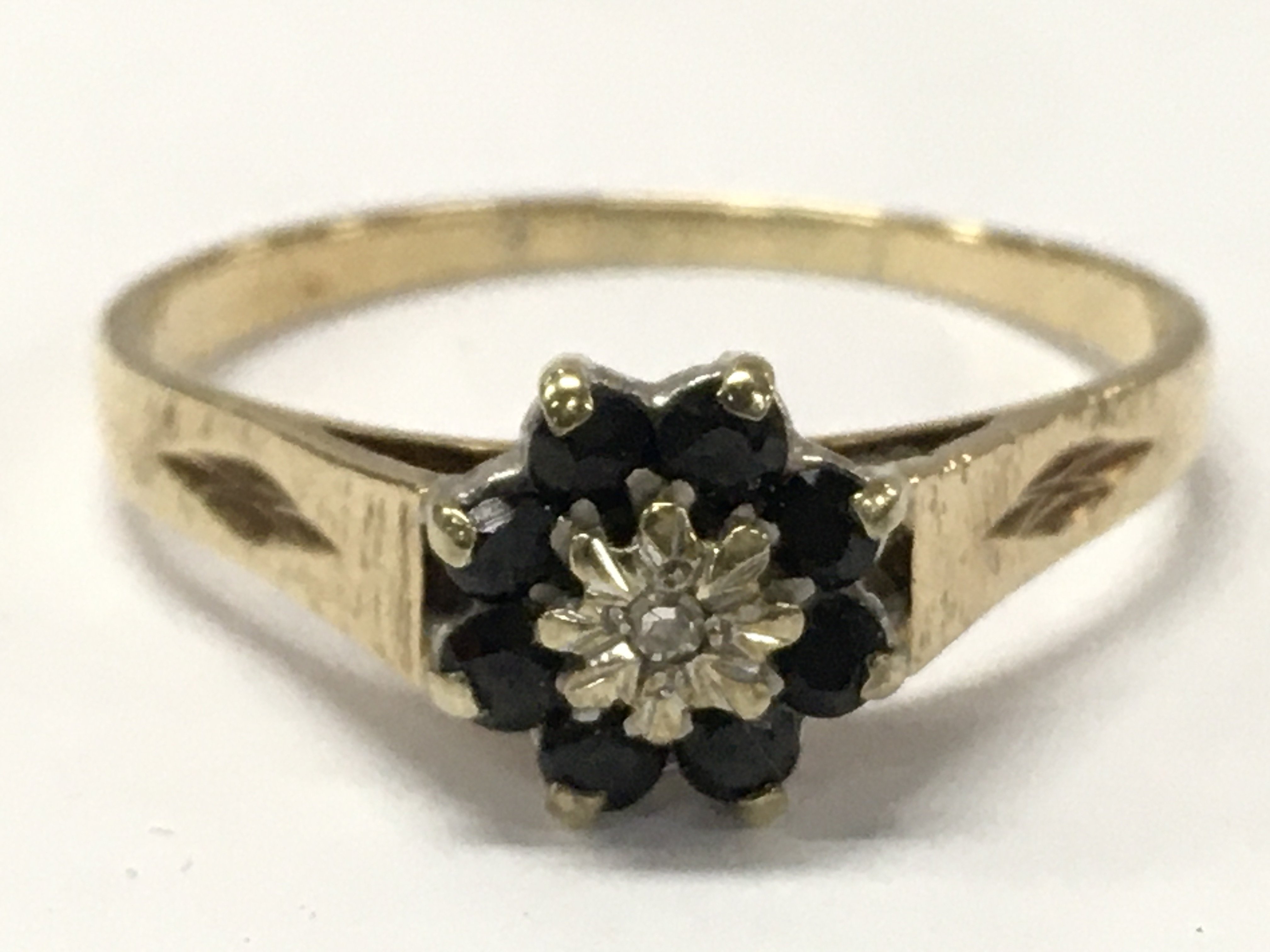 A 9ct gold flower pattern sapphire ring set with a central small diamond stone , size W. 2.5g total weight. Postage category A