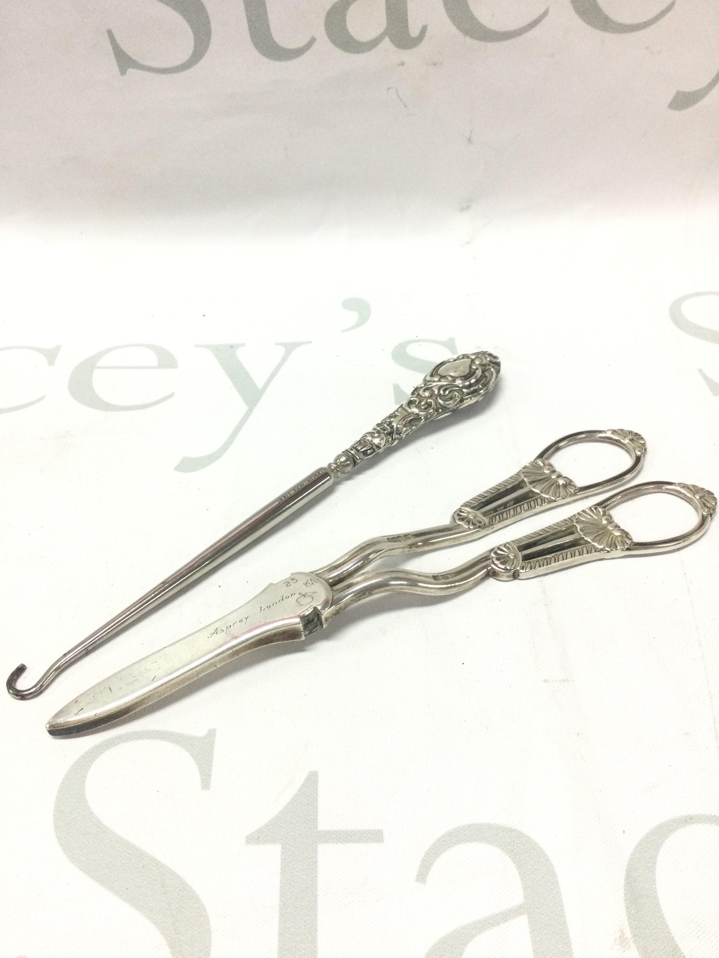 A pair of silver Asprey London grape scissors, silver handled button hook . Postage category B
