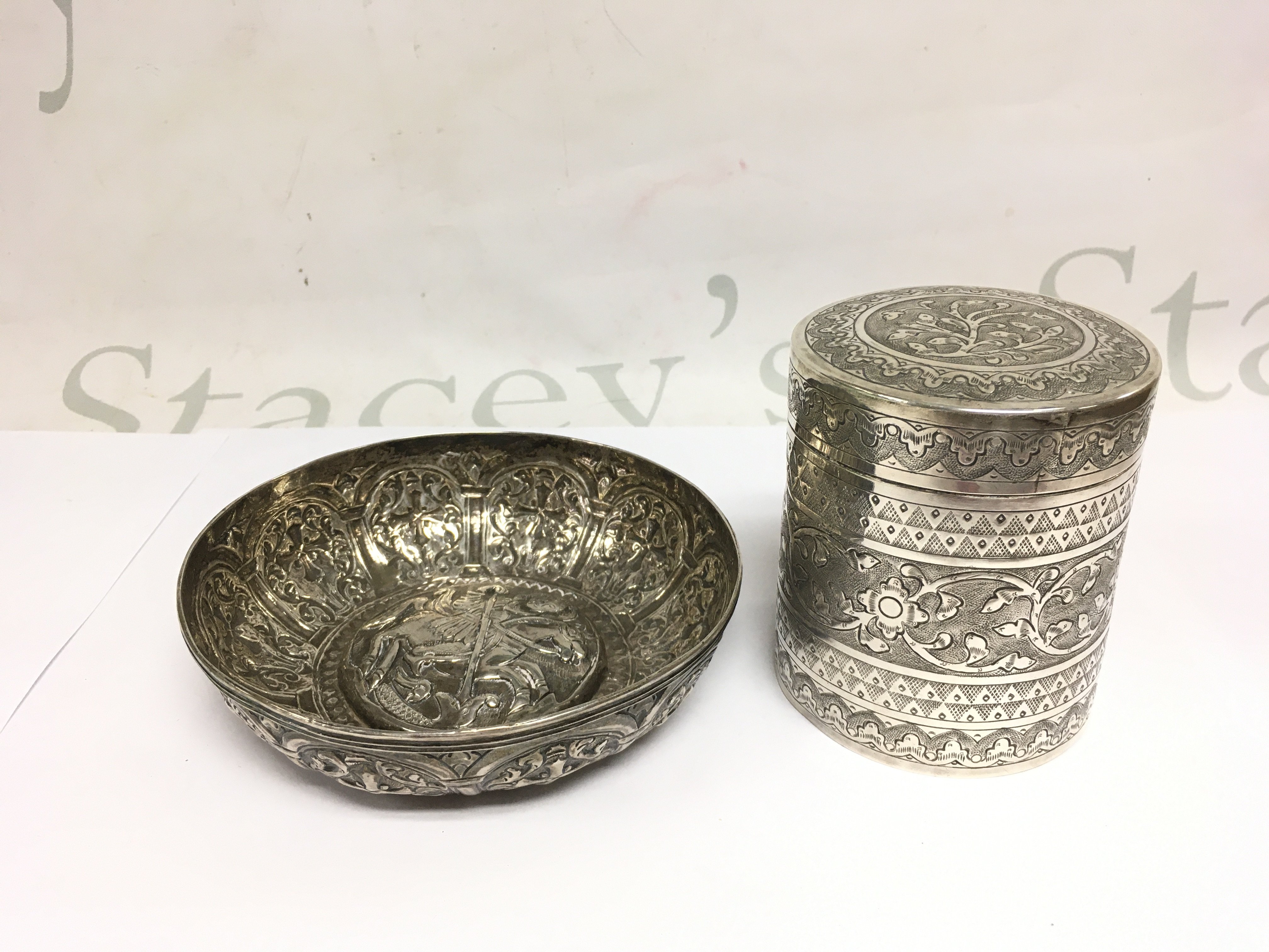 withdrawn - An embossed silver bowl of Indian influence depicting St George and the dragon to the centre, approx diameter 12.5cm plus a silver jar and cover, some damage. Shipping category B.