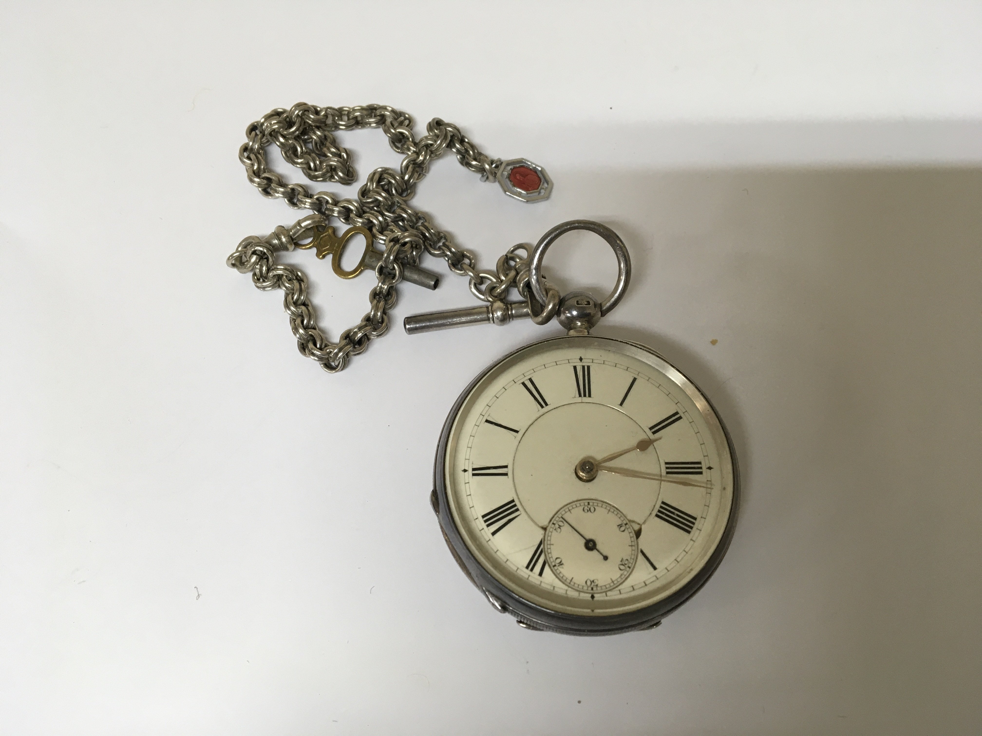 A silver cased Key wind Waltham Pocket watch with attached silver watch chain and white enamel dial.