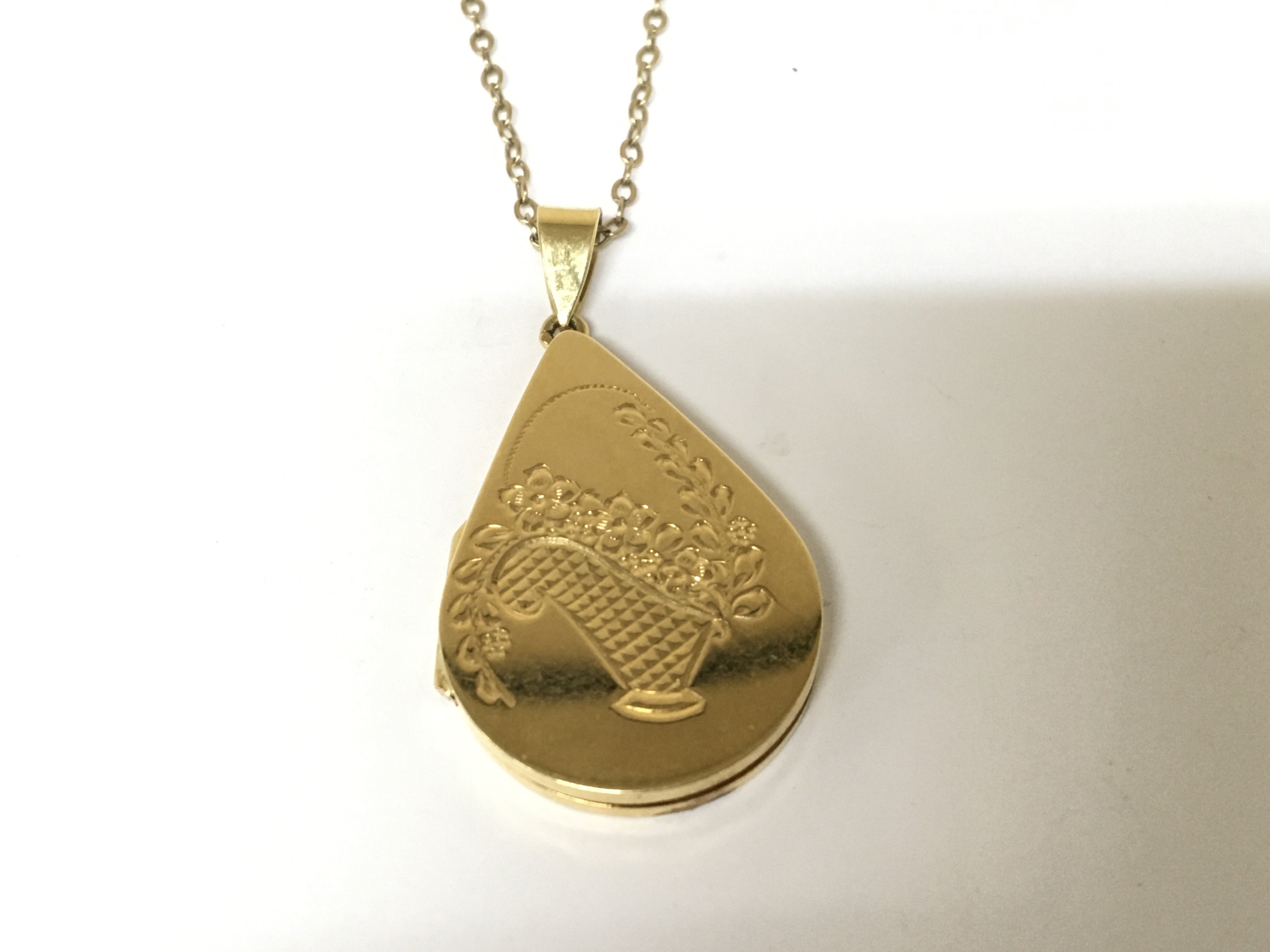 A boxed Mappin & Webb 18cart gold locket of pear shape etched with a basket of flowers weight 10g with an attached 9carat gold chain 1.8g