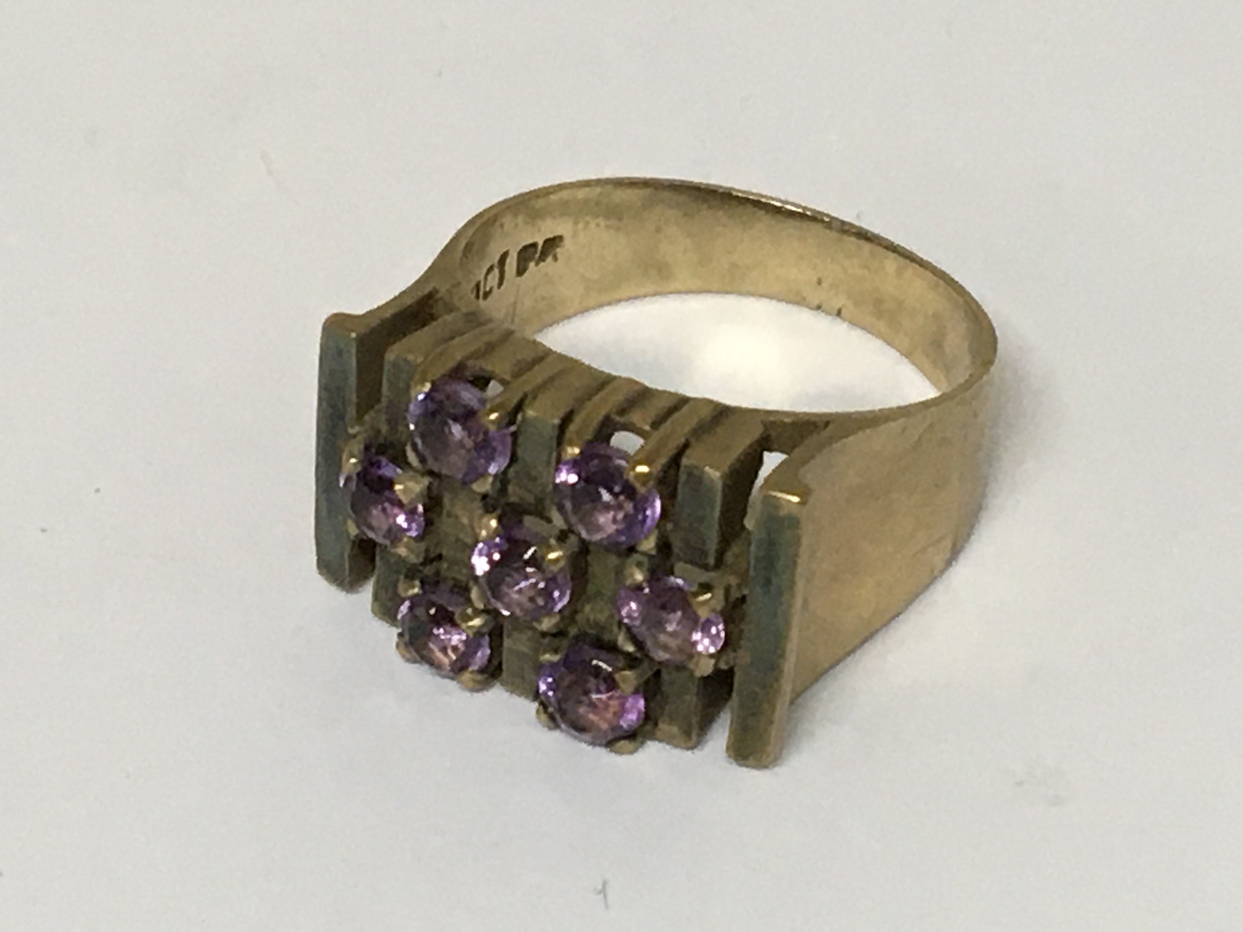 A 9carat gold modern design ring set with a pattern of amethyst stones. Weight 6.5g