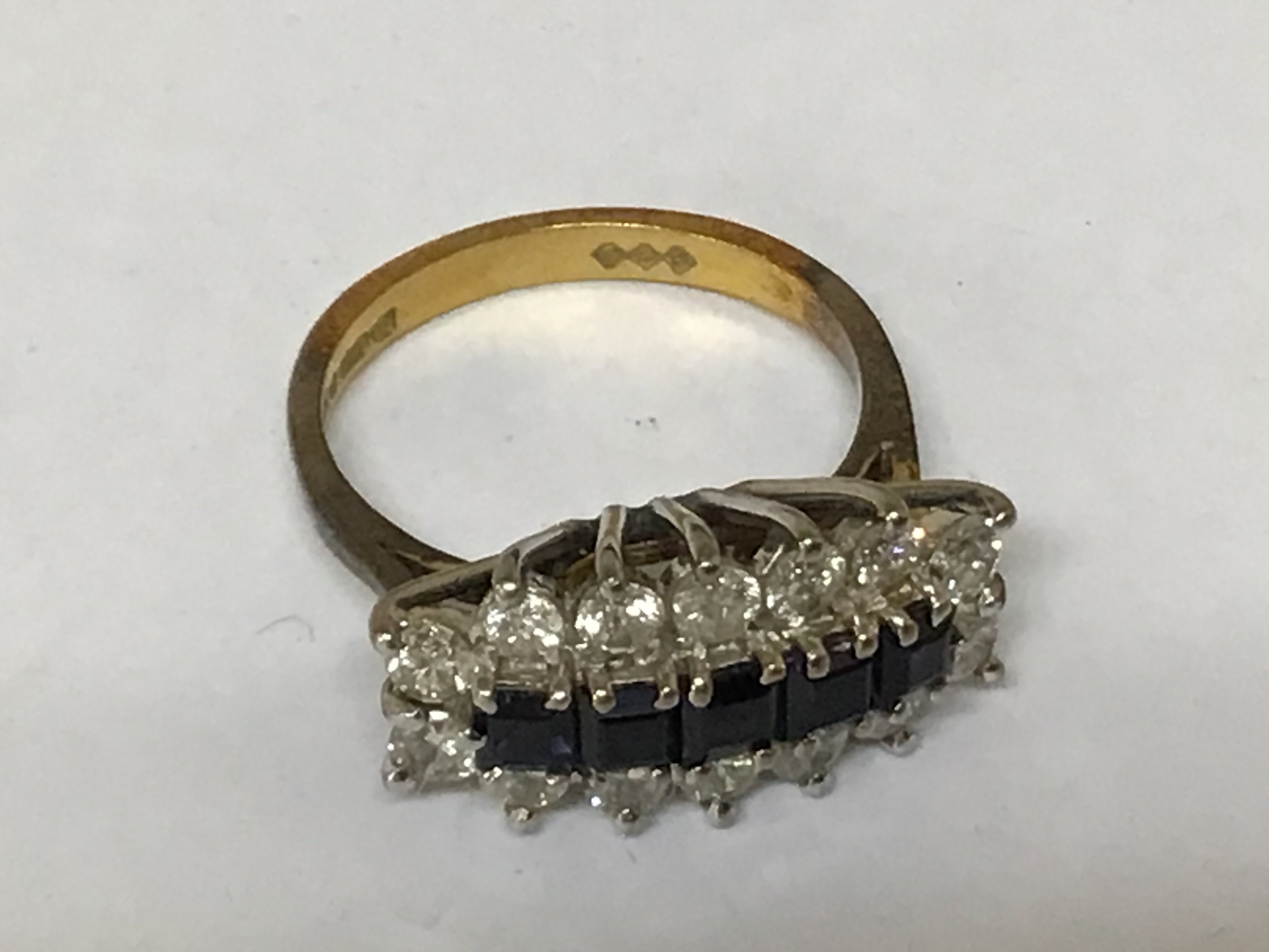 An 18carat gold ring set with a row of sapphire flanked by diamonds.weight 4g