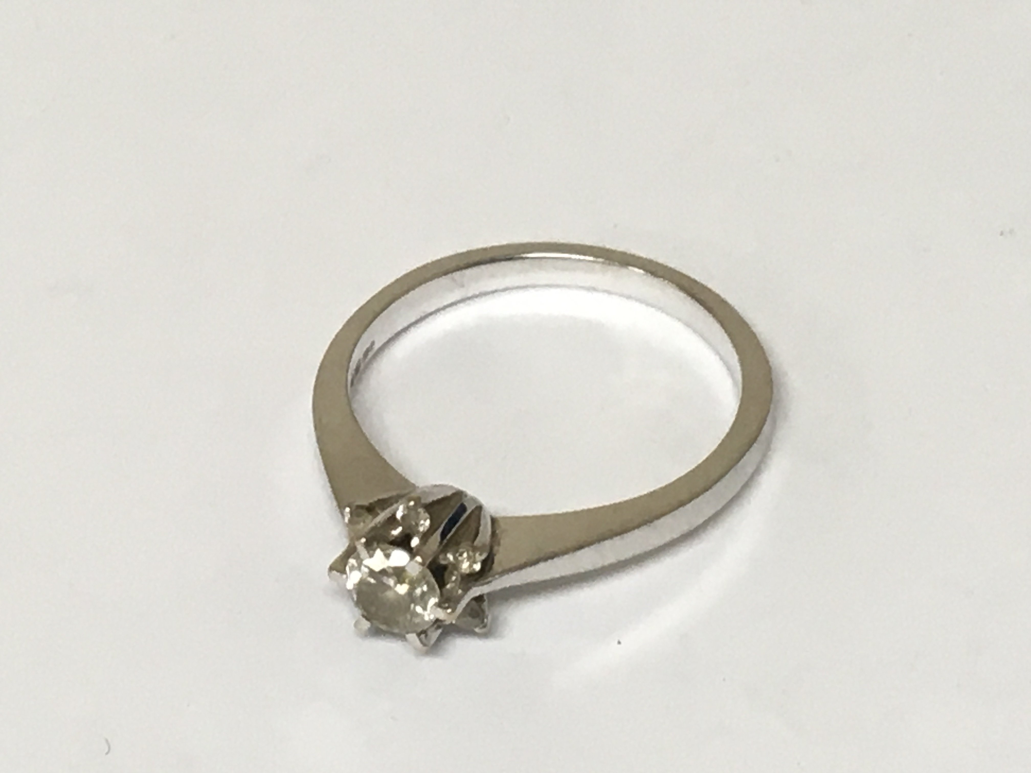 An 18carat gold ring set with a brilliant cut diamond approximately 0.3 flanked by smaller diamonds of a carat ring size P. Weight 3.7g